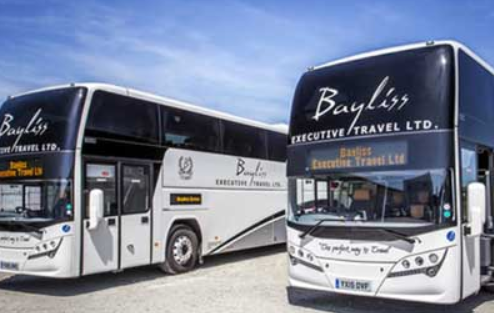 Two large BayLiss Executive Travel LTD buses parked outdoors under a blue sky.