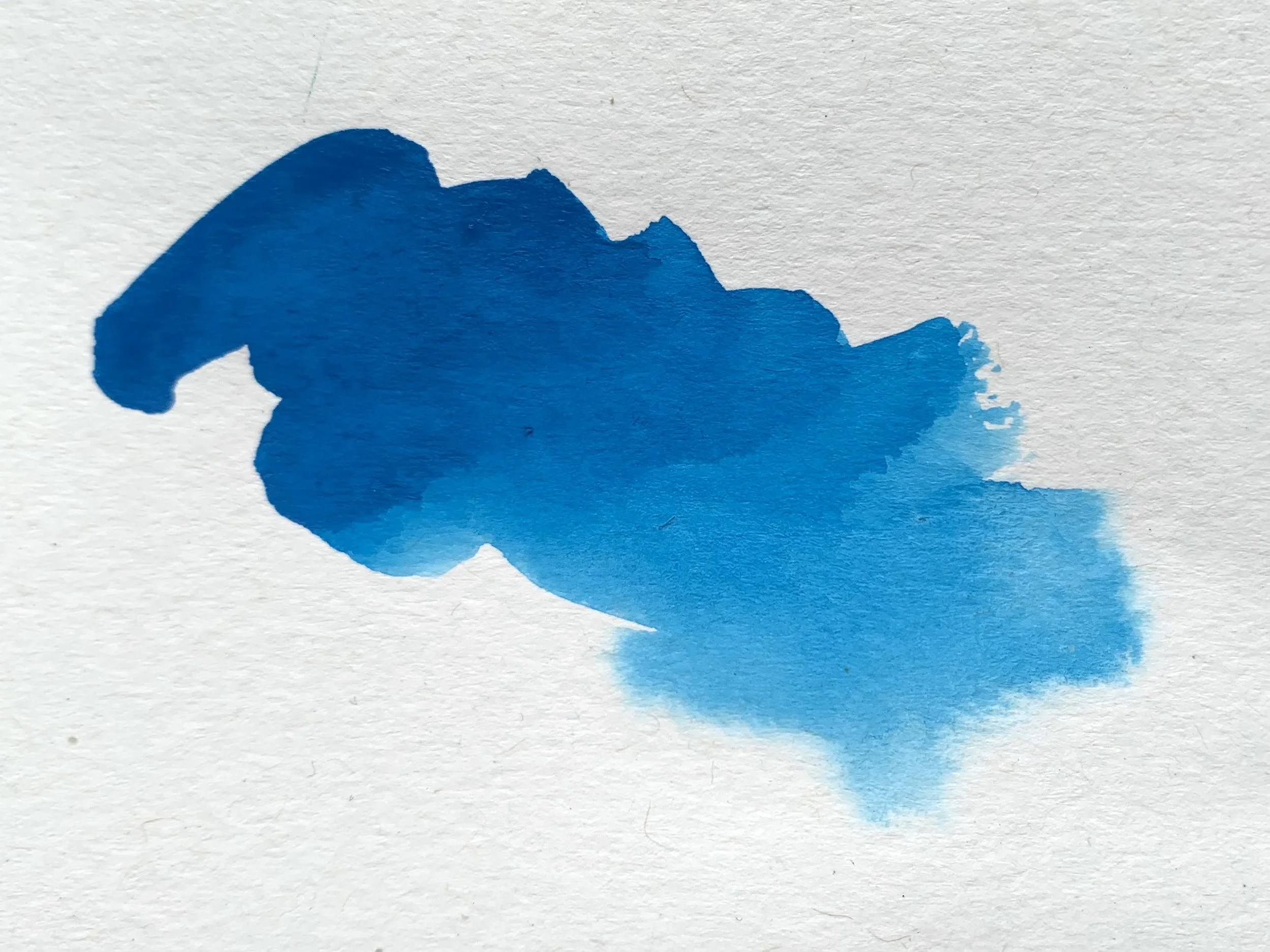 A swatch of bright blue watercolour on white textured paper.