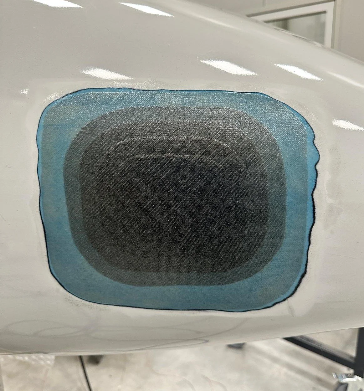 Close-up of a digital case sticker with a black square design, edged with a blue outline, on a white surface.