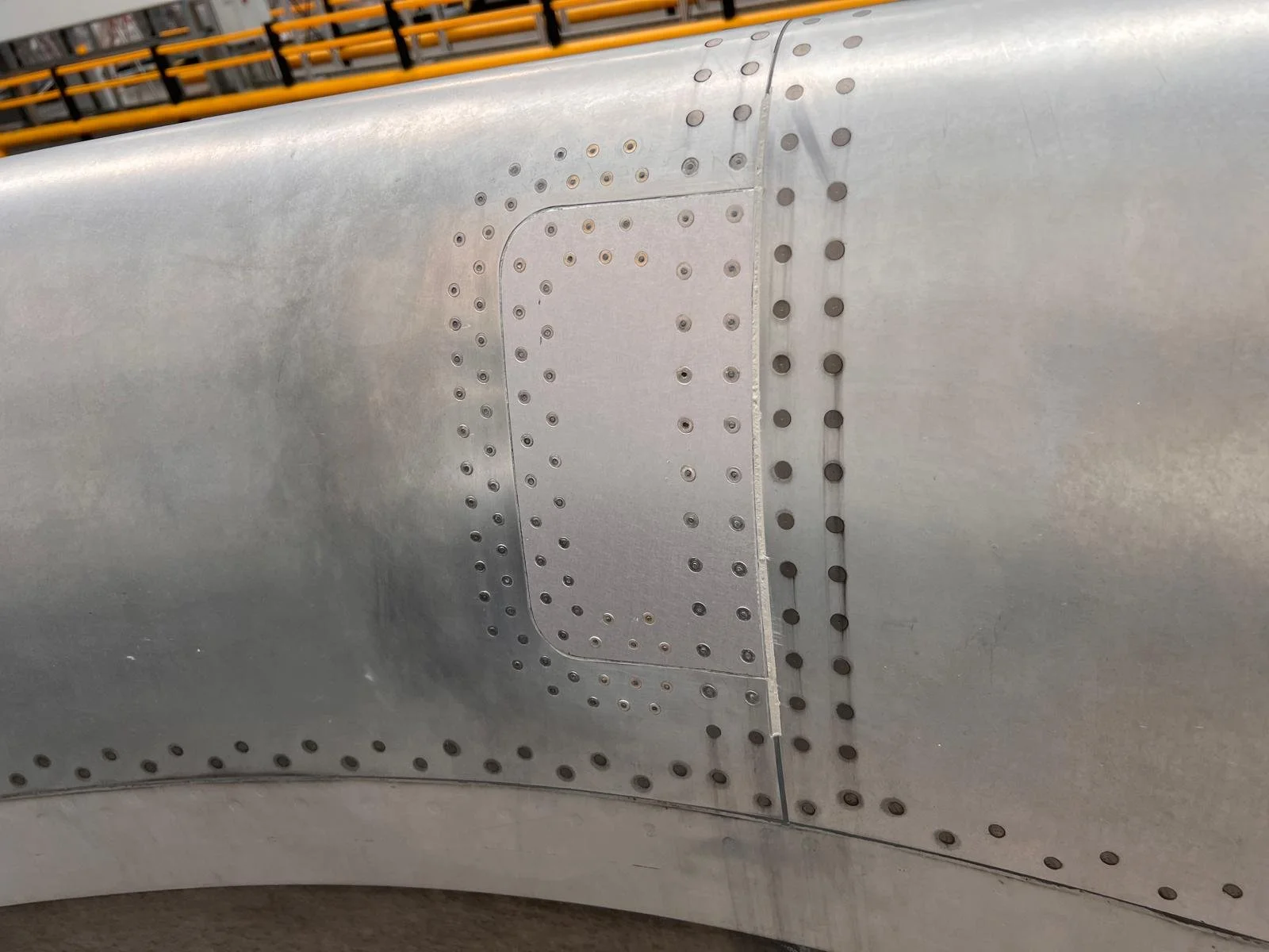 Close-up of an aircraft fuselage showing rivets and a hatch panel.