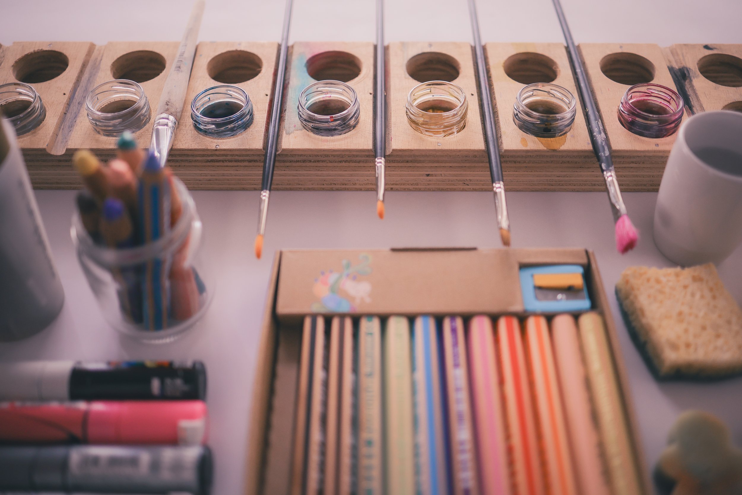 Palette de peinture avec des pinceaux, crayons de couleur, éponges, et autres fournitures d'art sur une table de bricolage.