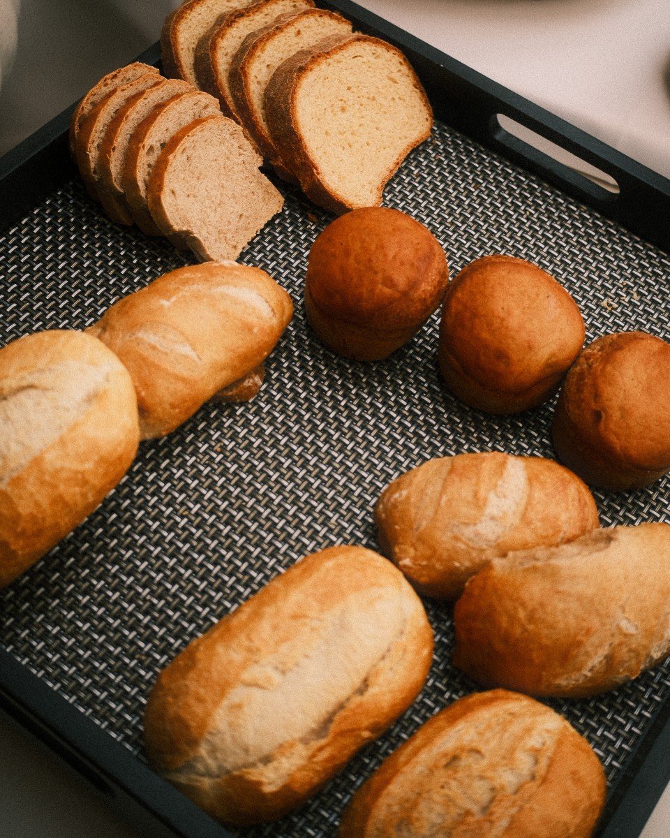 Verschiedene Brotsorten, inklusive Baguette, Toastbrot und Brötchen, auf einem Gebäckkorb.