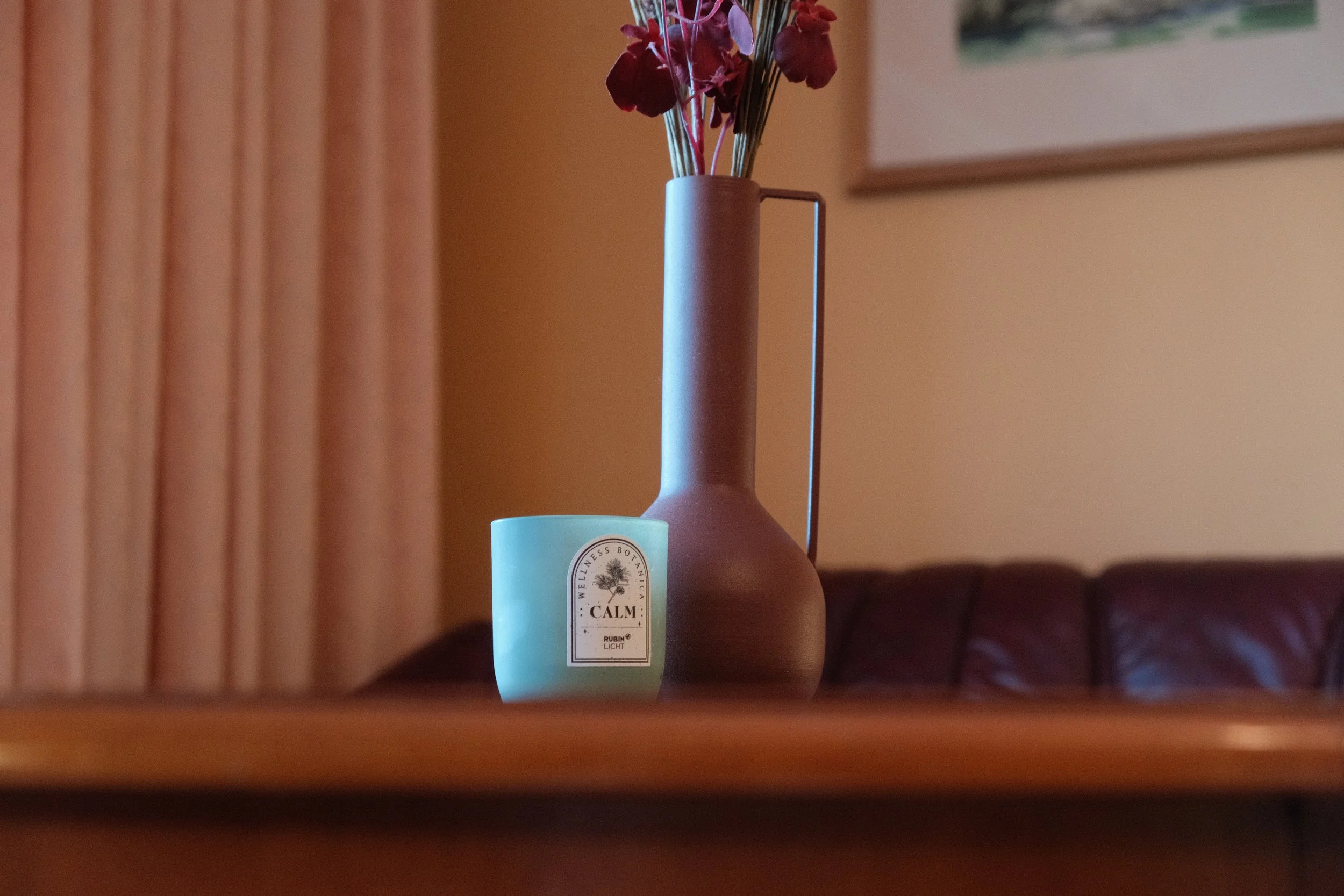 Ein brauner Keramikvase mit roten Blumen und eine weiße Kerze mit 