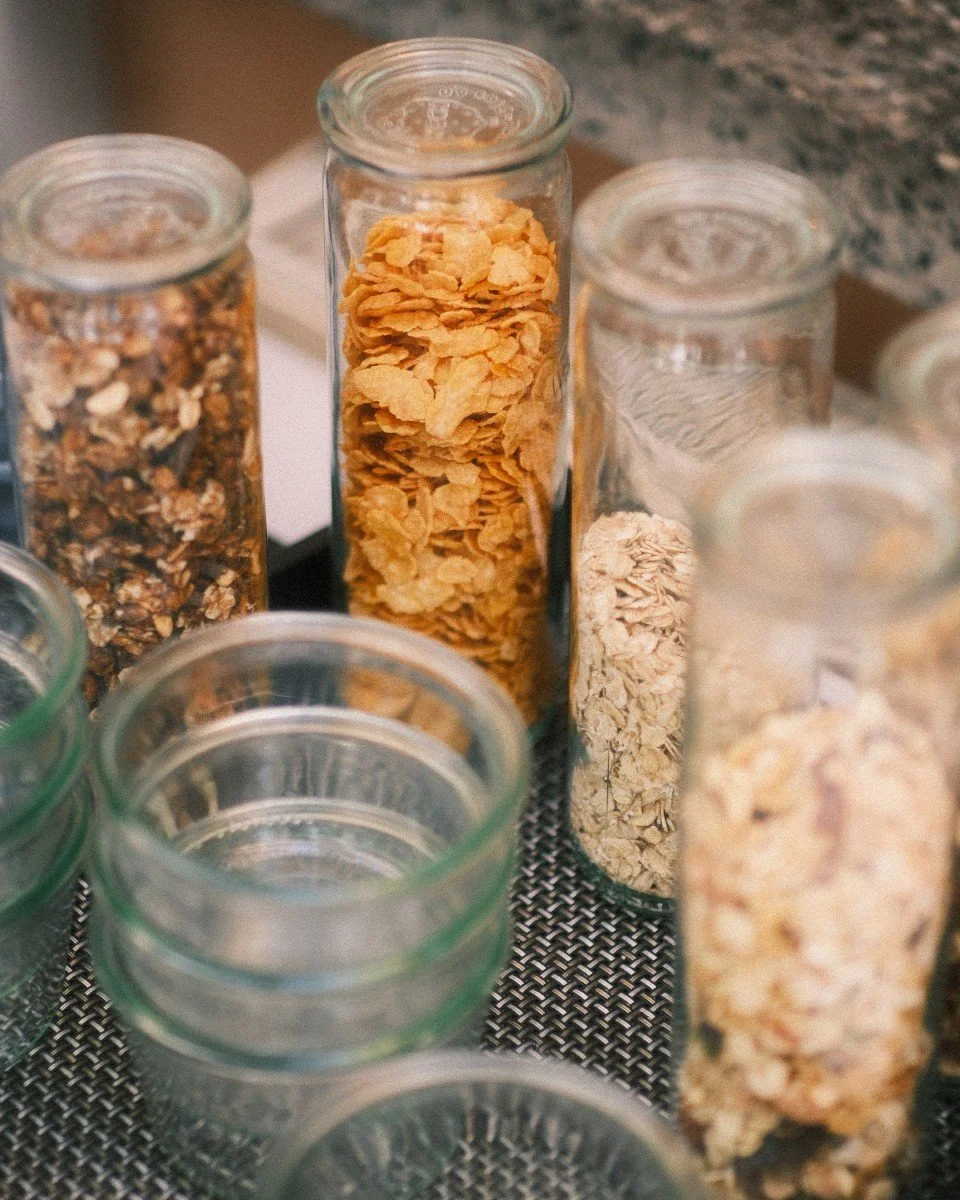 Verschiedene Glasbehälter mit Müsli und Cornflakes auf einer dunklen Textilunterlage