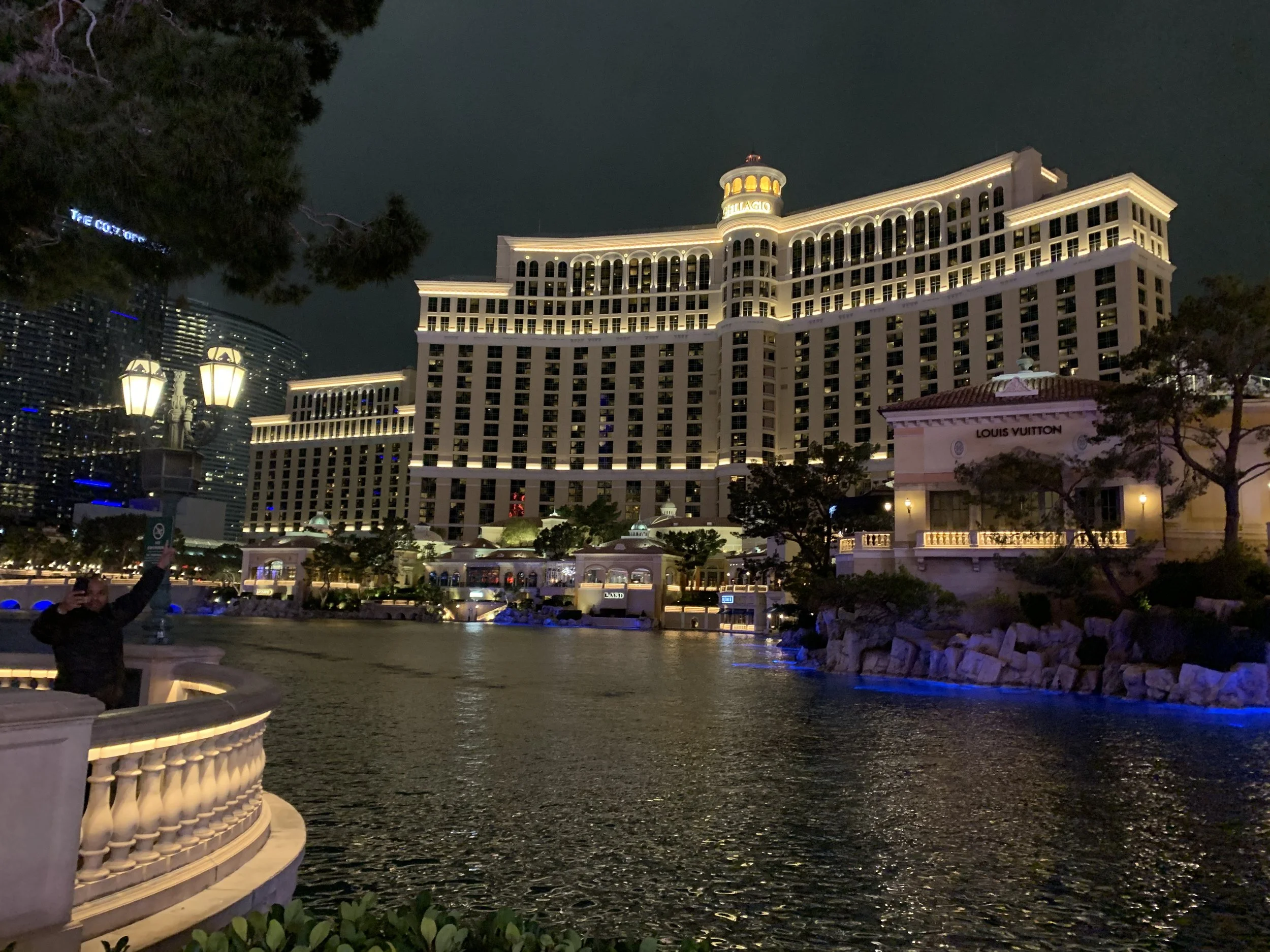 Bellagio Hotel and Louis Vuitton store illuminated at night over the fountain lake in Las Vegas.