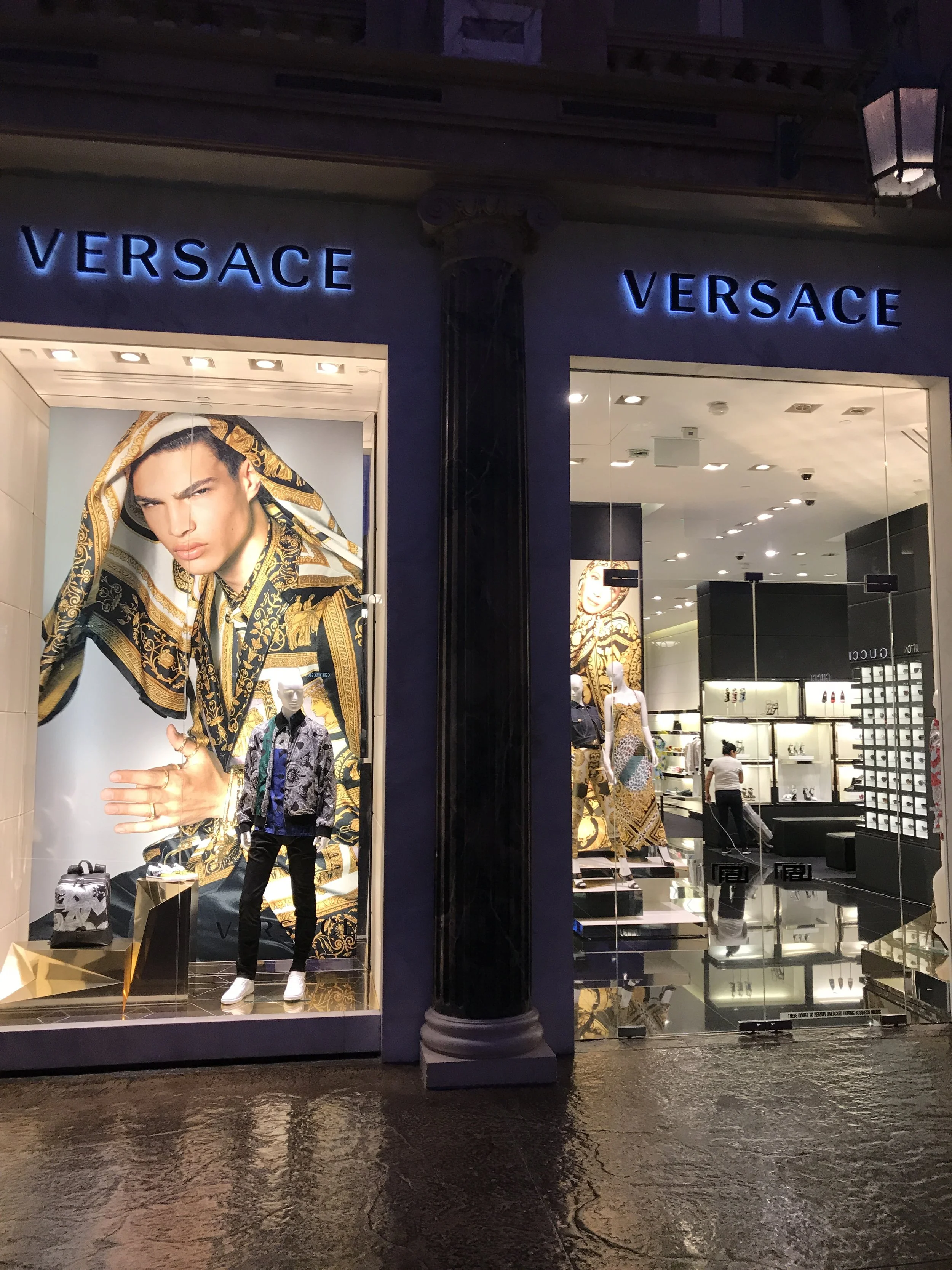 Versace boutique entrance at The Forum Shops with glowing blue signs and high-fashion window displays in Las Vegas.