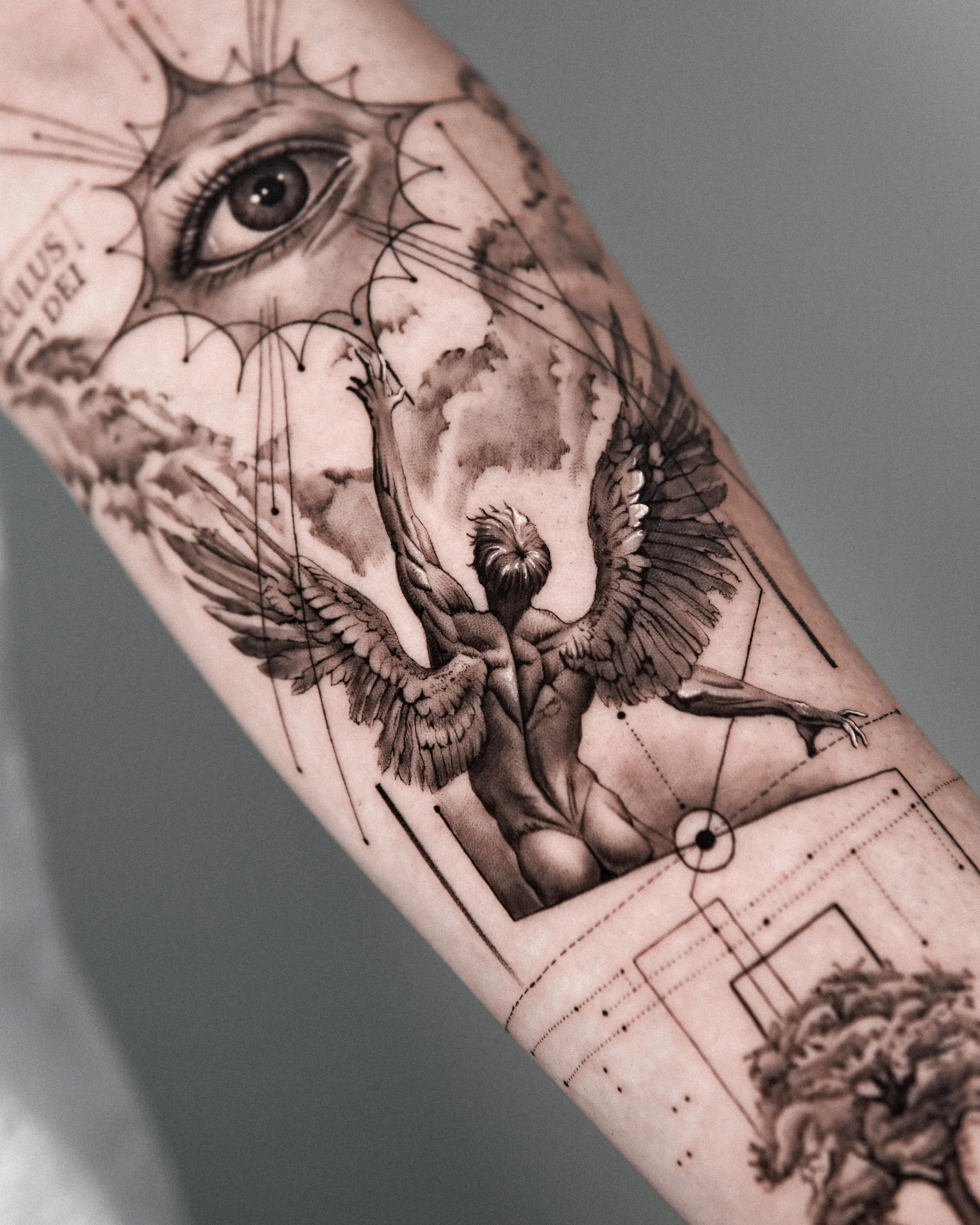 Close-up of a tattoo on a person's arm featuring a detailed eye, geometric lines, and artistic shading.