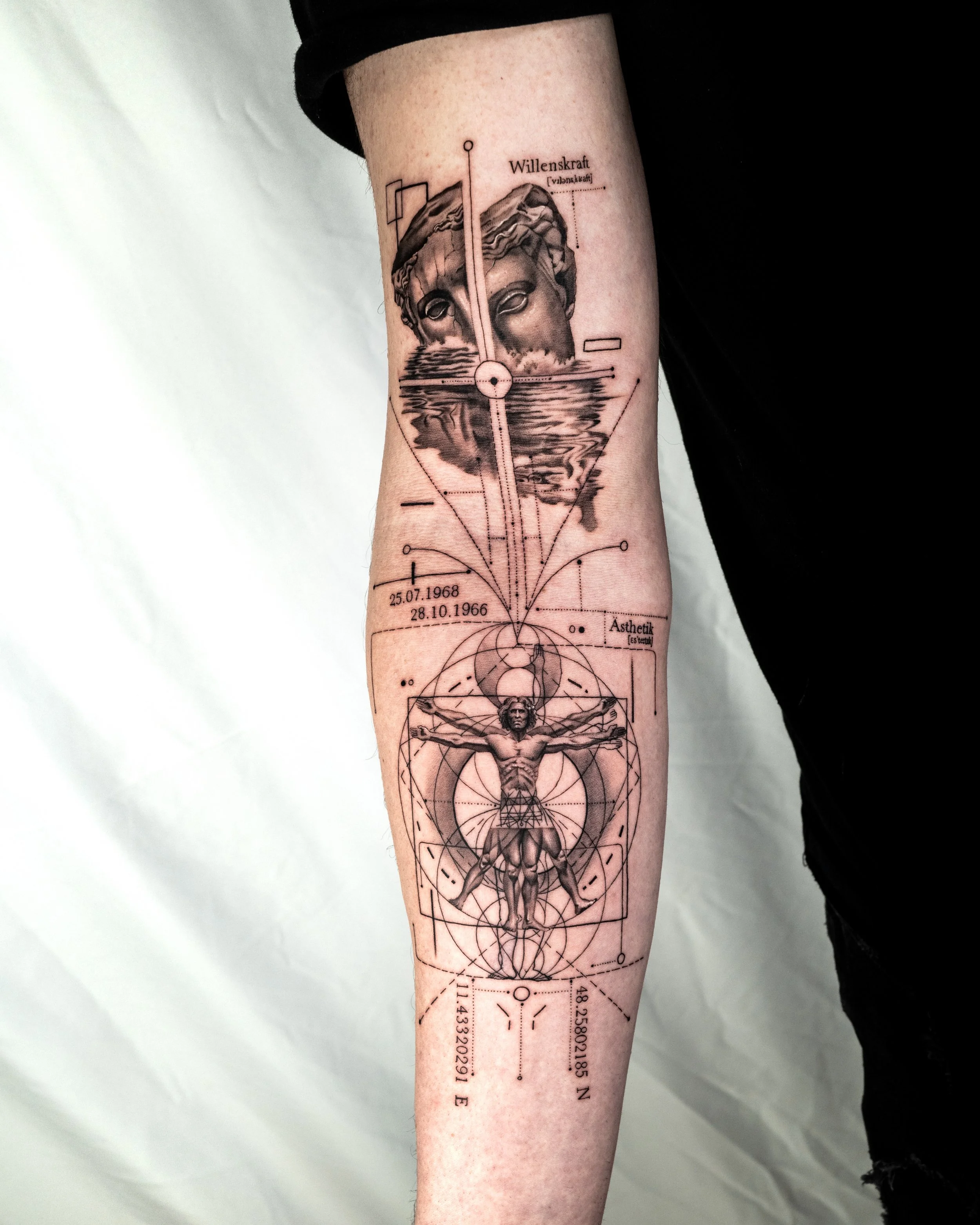 Tattoo on forearm featuring a classical sculpture head, geometric shapes, technical lines, and numerical data, with the word "Willenskraft" at the top.