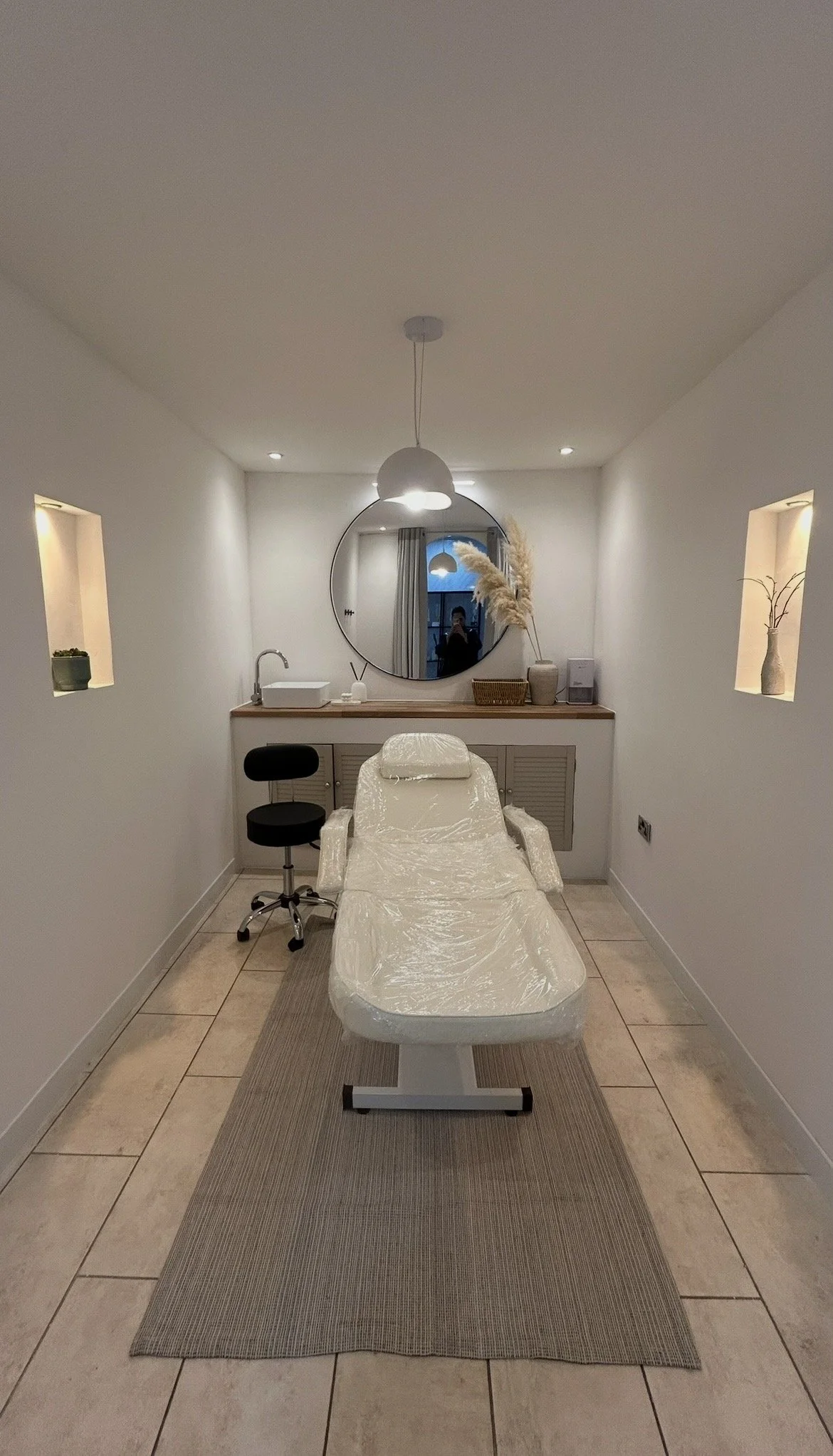 Medical treatment room with a bed, mirror, and decorative items.