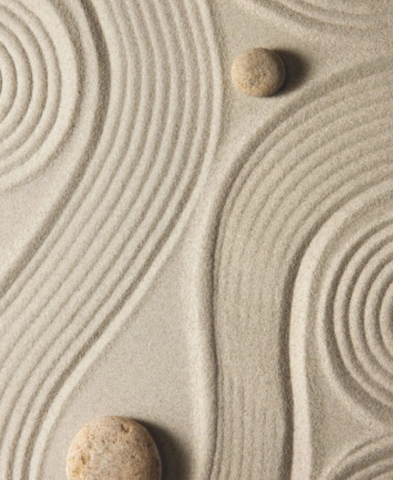 A Zen garden with raked sand in concentric circles and patterns, featuring two small rocks.