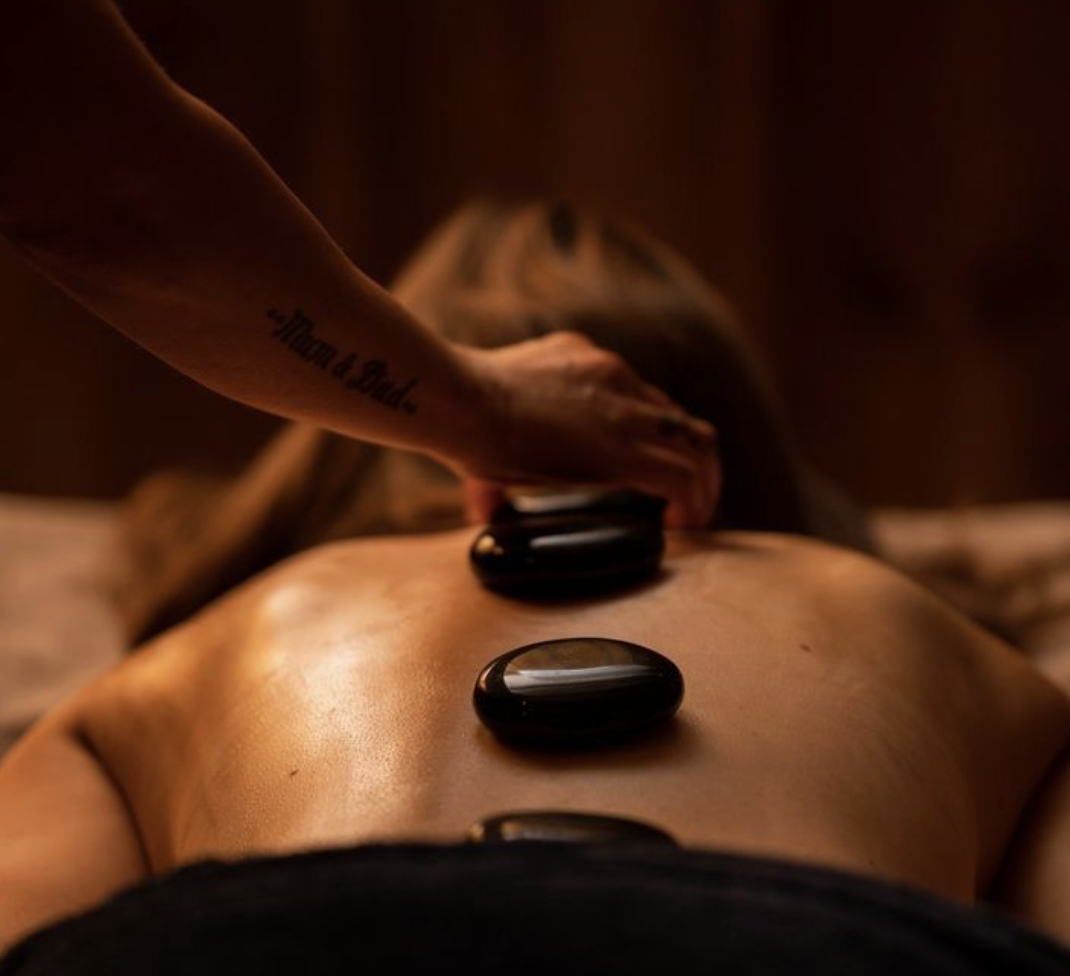 Person receiving hot stone massage on their back in a spa setting.