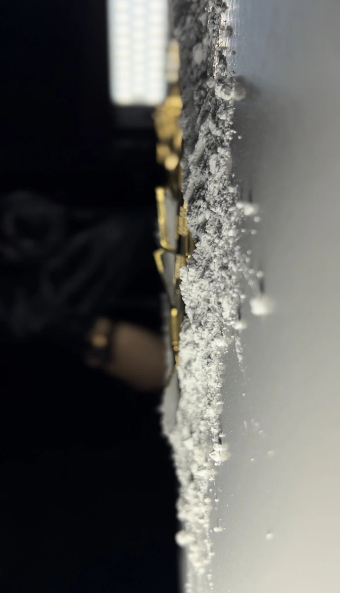 Close-up of a cement covered surface with part of a gold-colored nail tools and black fabric in the background.