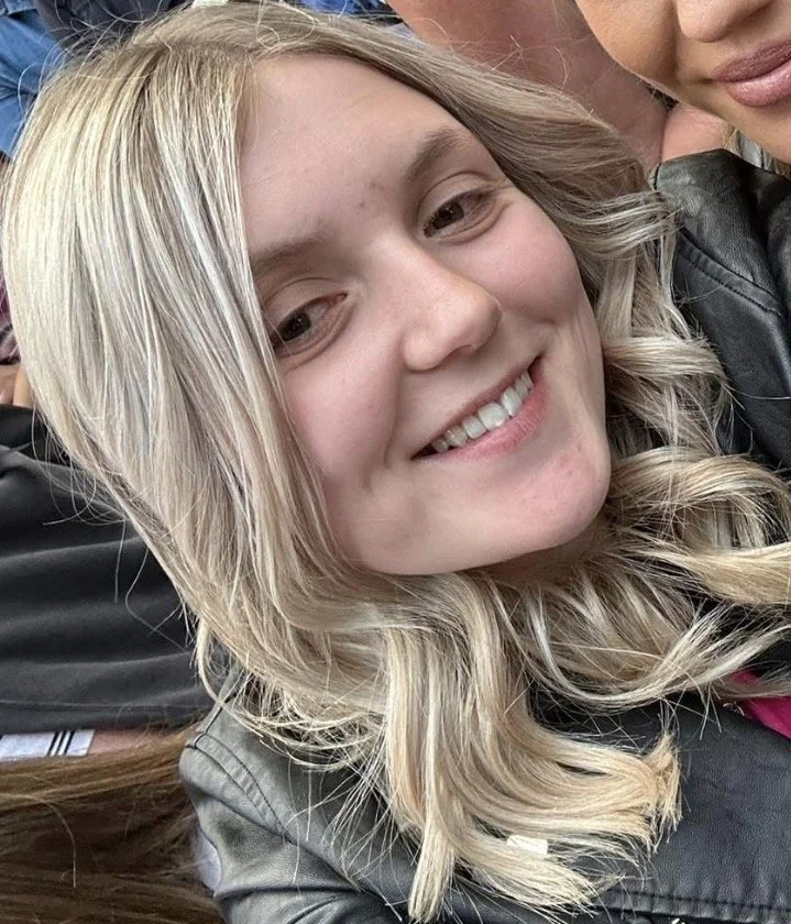 Close-up of a young woman with blonde hair smiling.