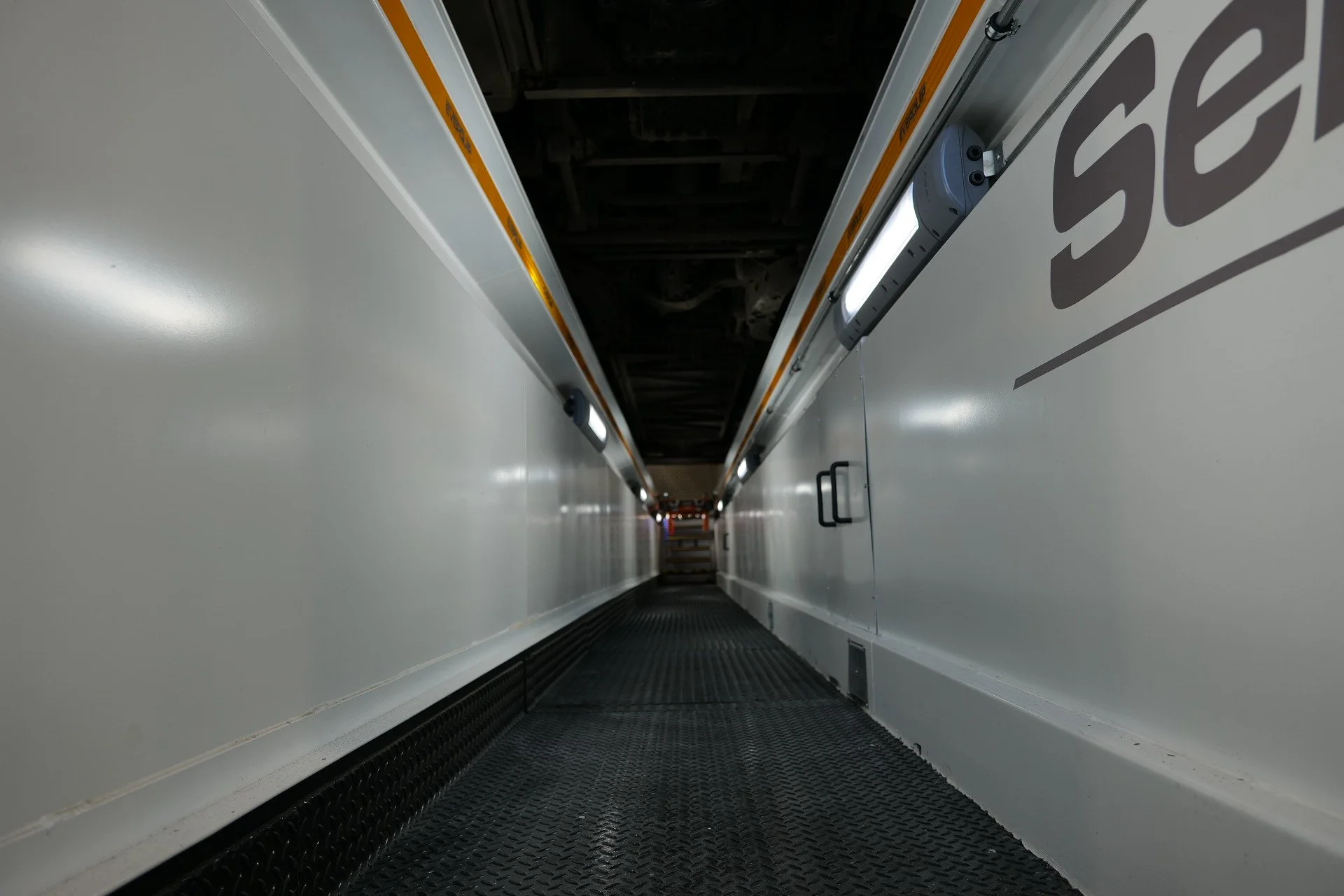 A vintage bus parked in a parking lot, with a gray and orange color scheme and the words 'A.C.L.A.N.D. & B. Beasley' written on the side.