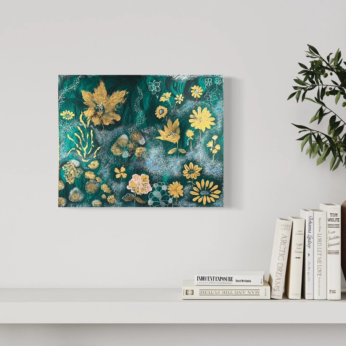 A colorful abstract painting featuring gold and pink flowers, green leaves, and a swirling teal background, hung on a white wall above a shelf with books.