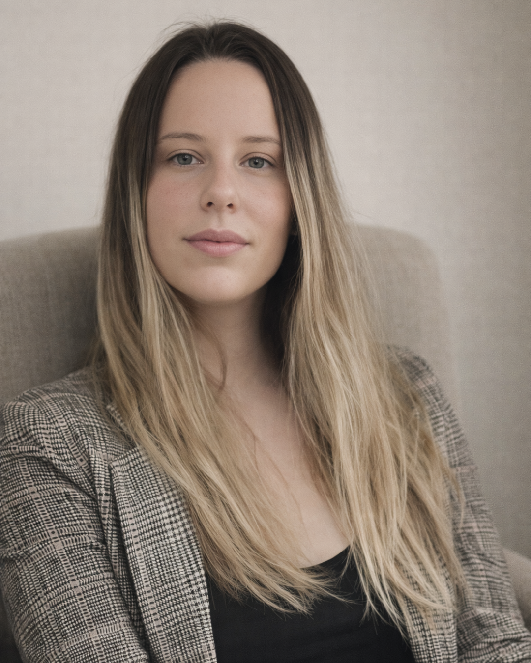 Hannah ONeill sitting on a sofa with long hair and a brown jacket