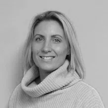 Black and white portrait of a woman with shoulder-length hair, smiling, wearing a turtleneck sweater.