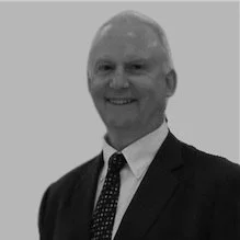 Black and white photo of a smiling man in a suit and tie.
