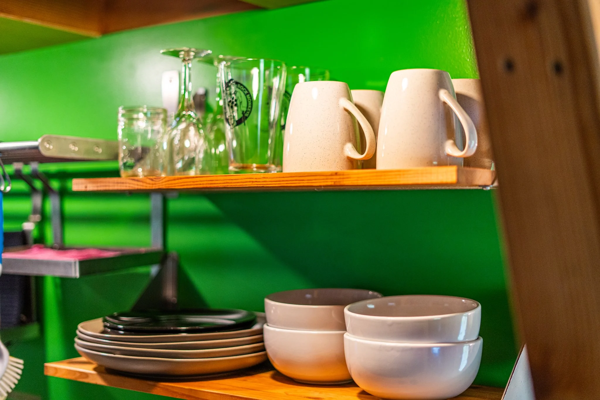 Kitchen shelves with drinking glasses, coffee mugs, bowls, and plates in the unique yurt at New River Nooks WV