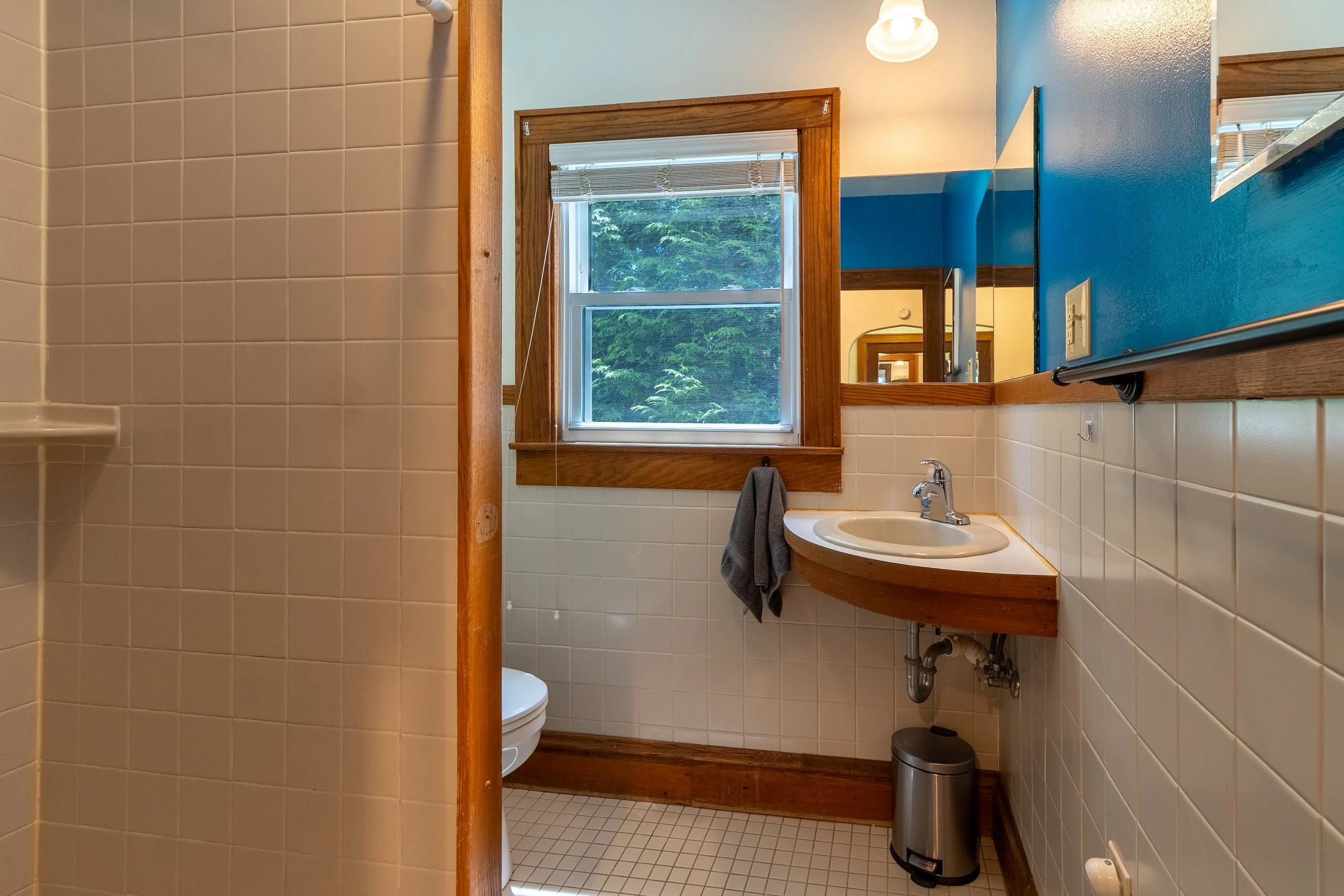 Bathroom at the pet-friendly cozy cottage on maple with full shower and sink at New River Nooks in New River Gorge, WV.