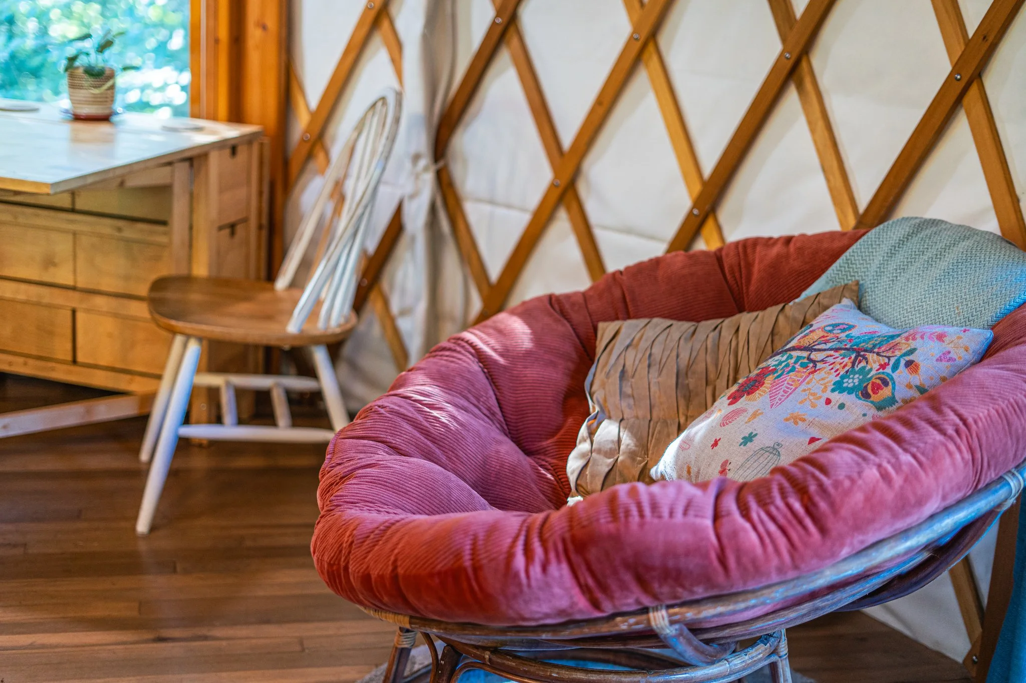 Cozy red cushioned papasan chair inside the unique yurt vacation rental at New River Nooks in New River Gorge WV