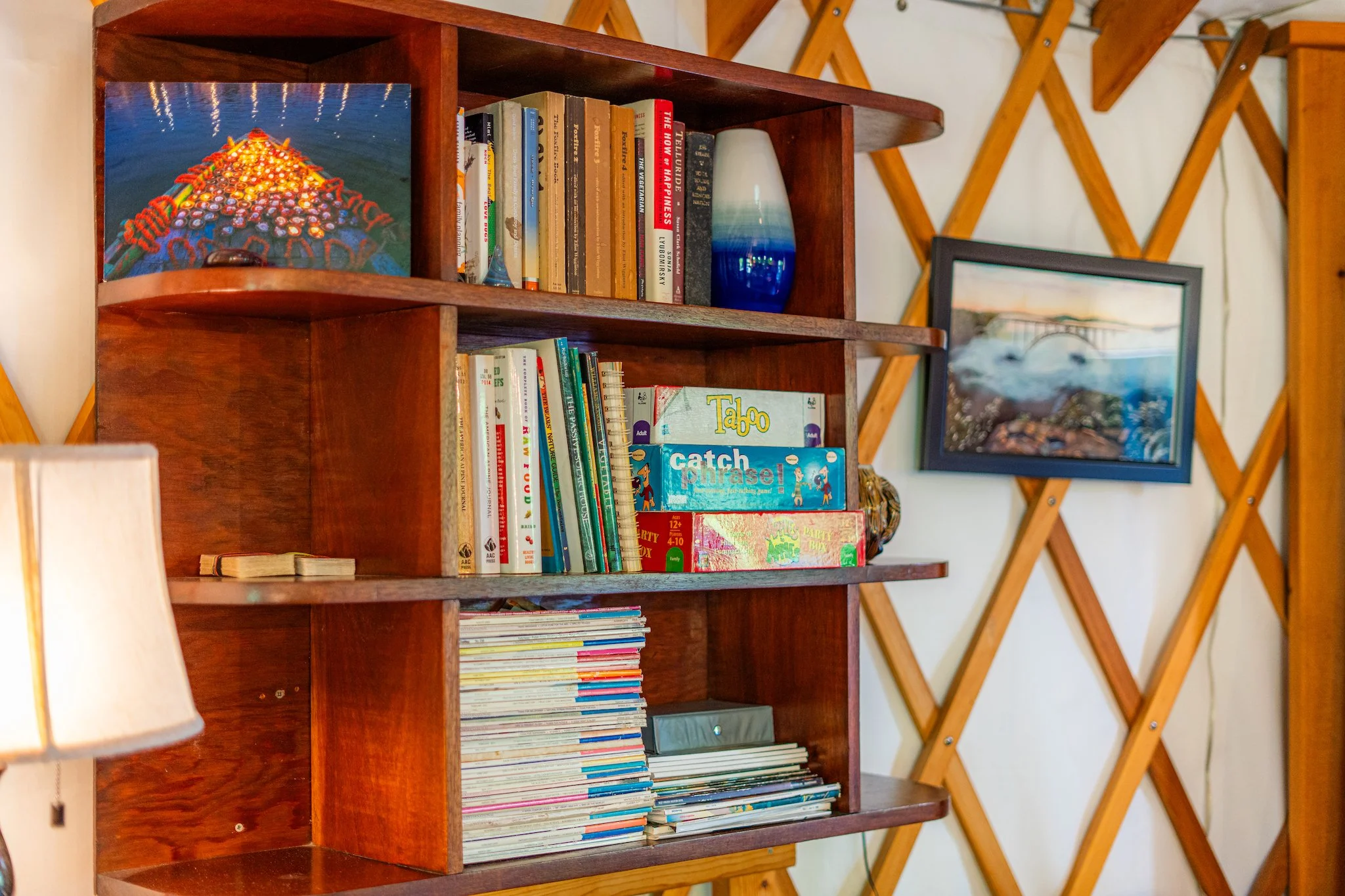 A wooden bookshelf filled with books, magazines, and games in the unique yurt vacation rental in New River Gorge WV