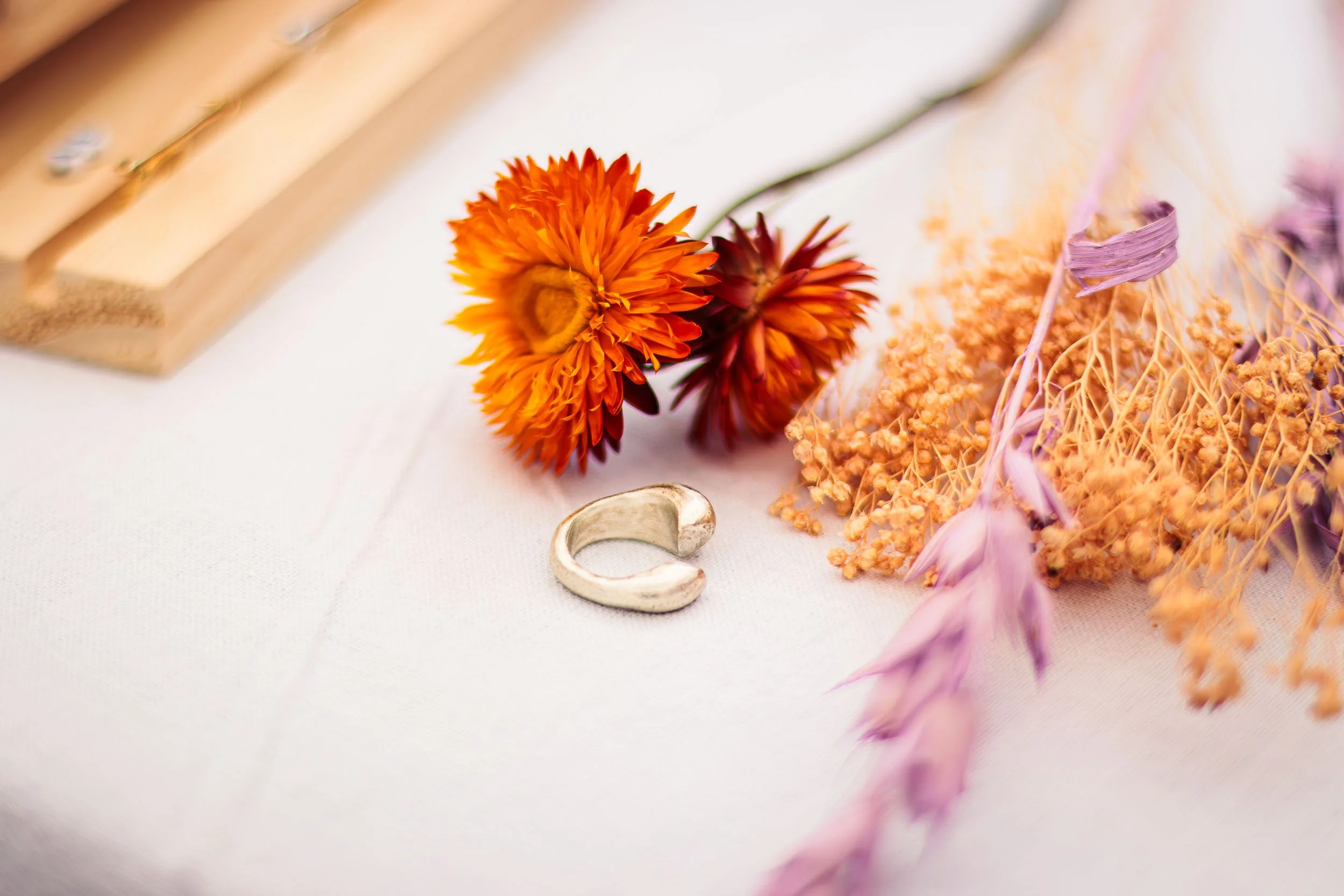 Minimal product flat lay with silver ring and orange flowers on a light background