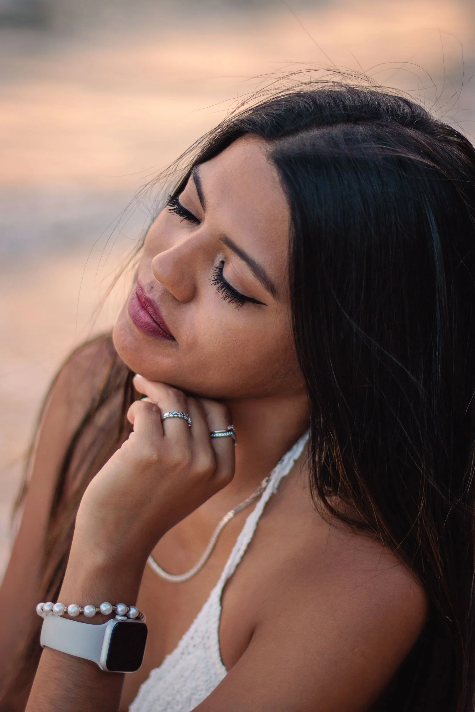 Close-up portrait of a woman looking down during a beach portrait session at sunset