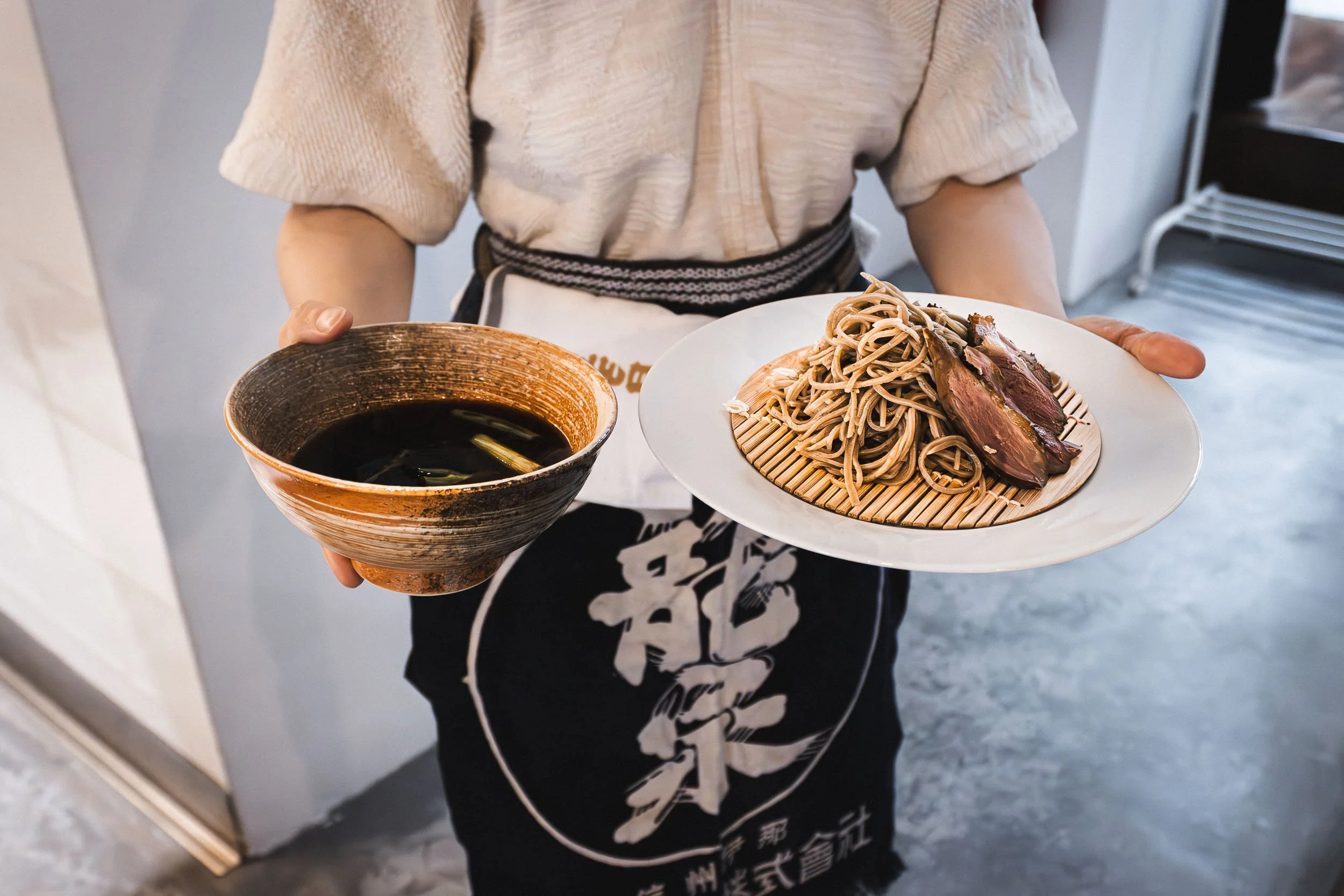 Overhead view of a waitress carrying Japanese Soba noodles and a broth