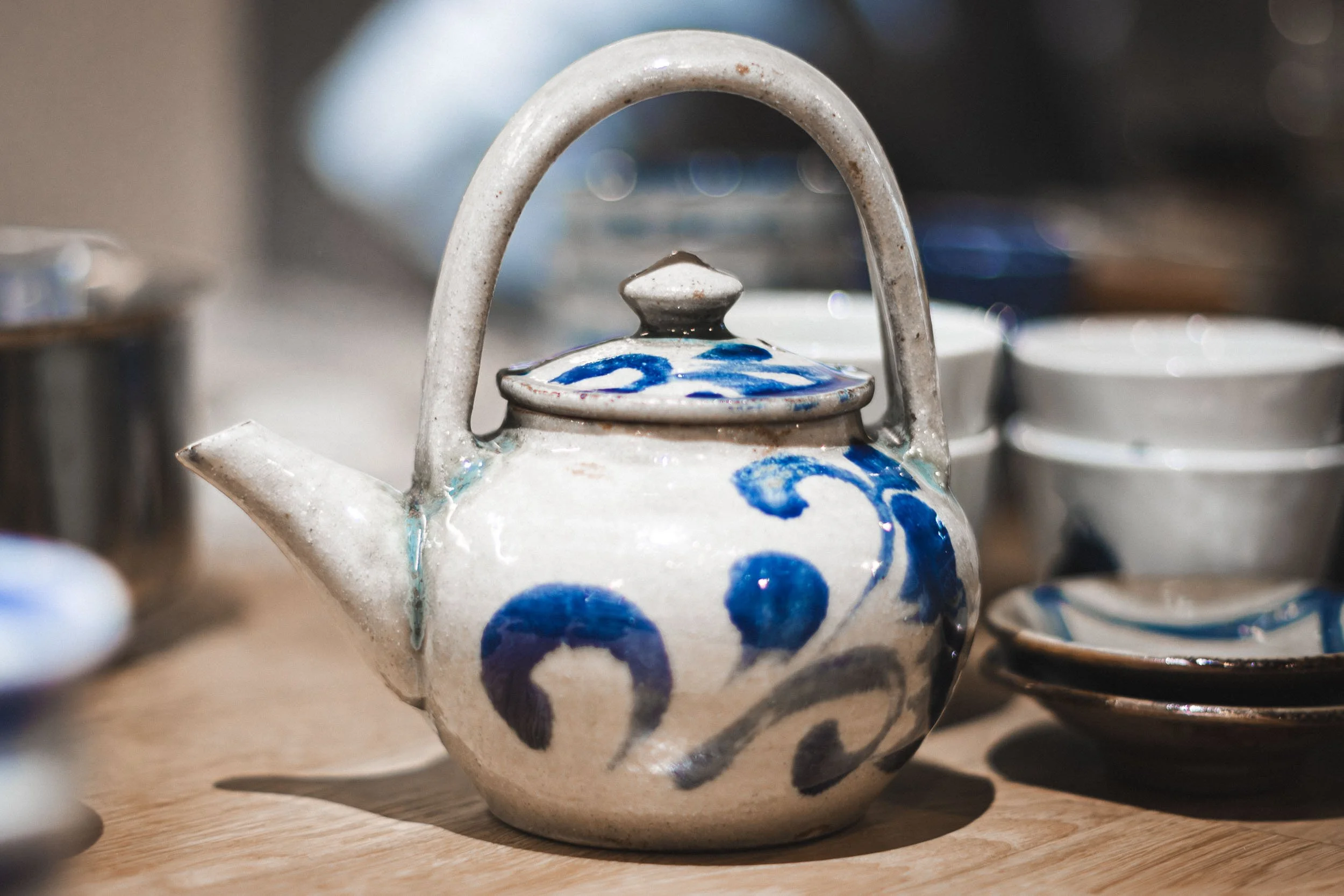 Ambience restaurant detail showing blue and white ceramic teapot on a wooden table 