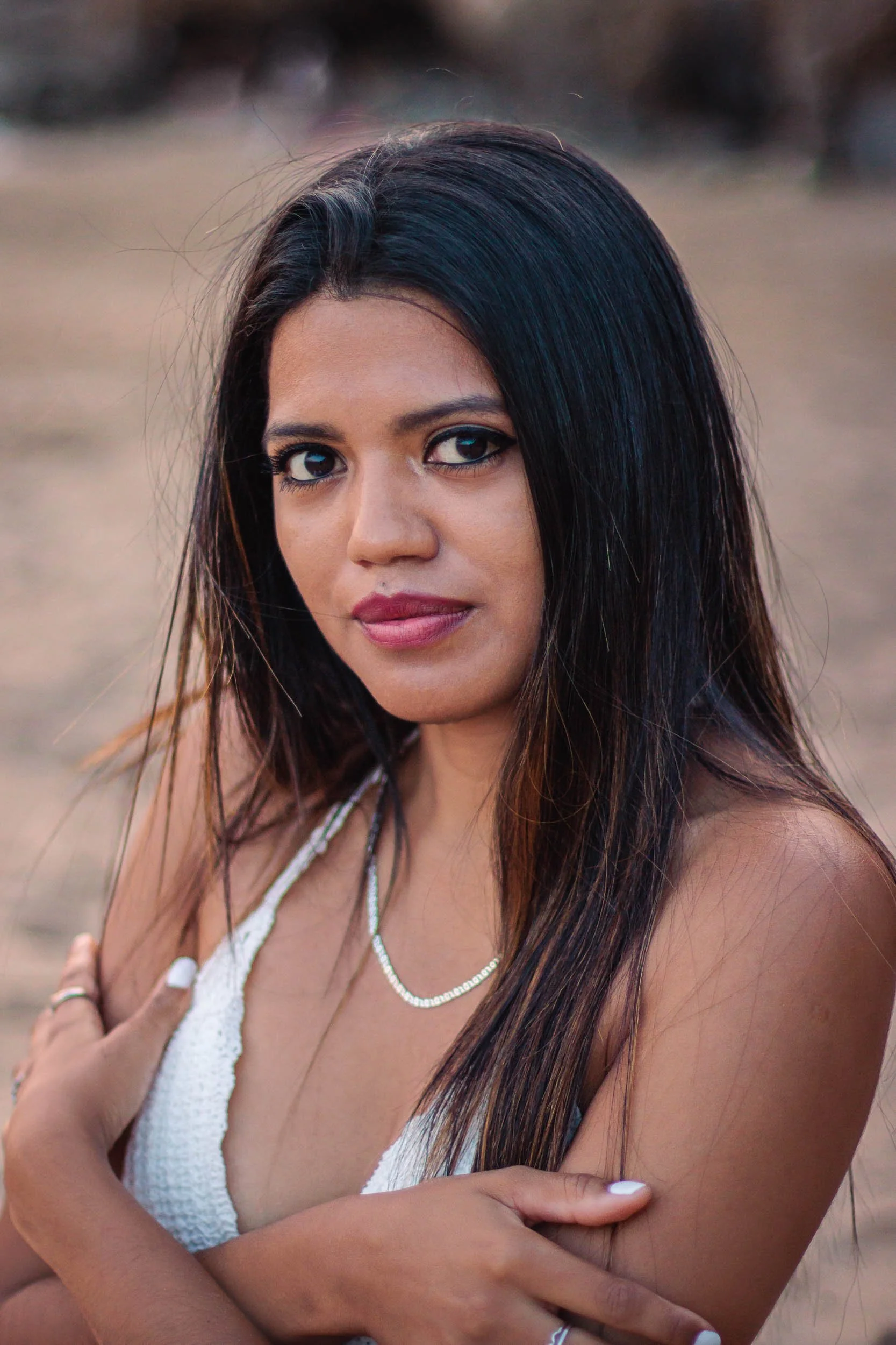 Close portrait of a woman sitting on the beach and looking toward the camera