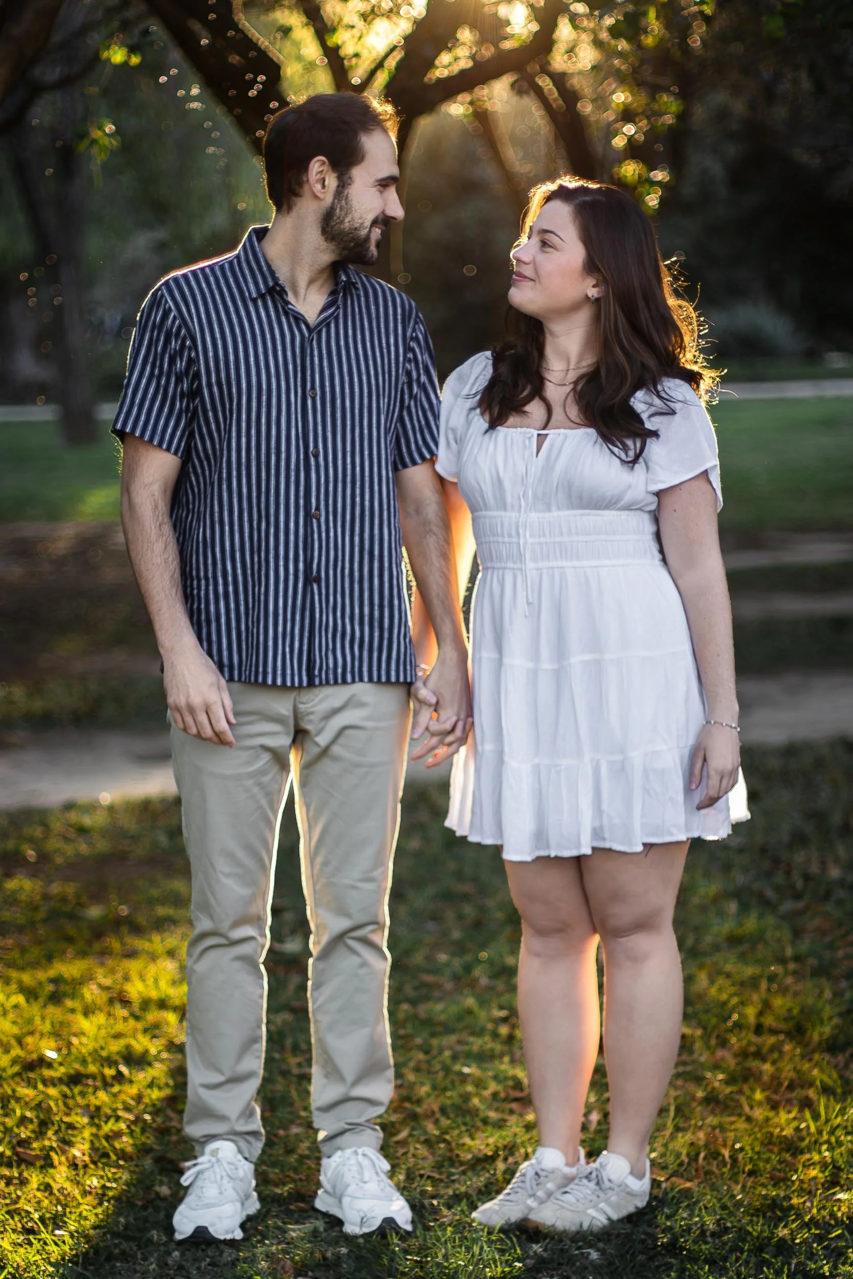 Full-length portrait of a couple standing together in a park at golden hour