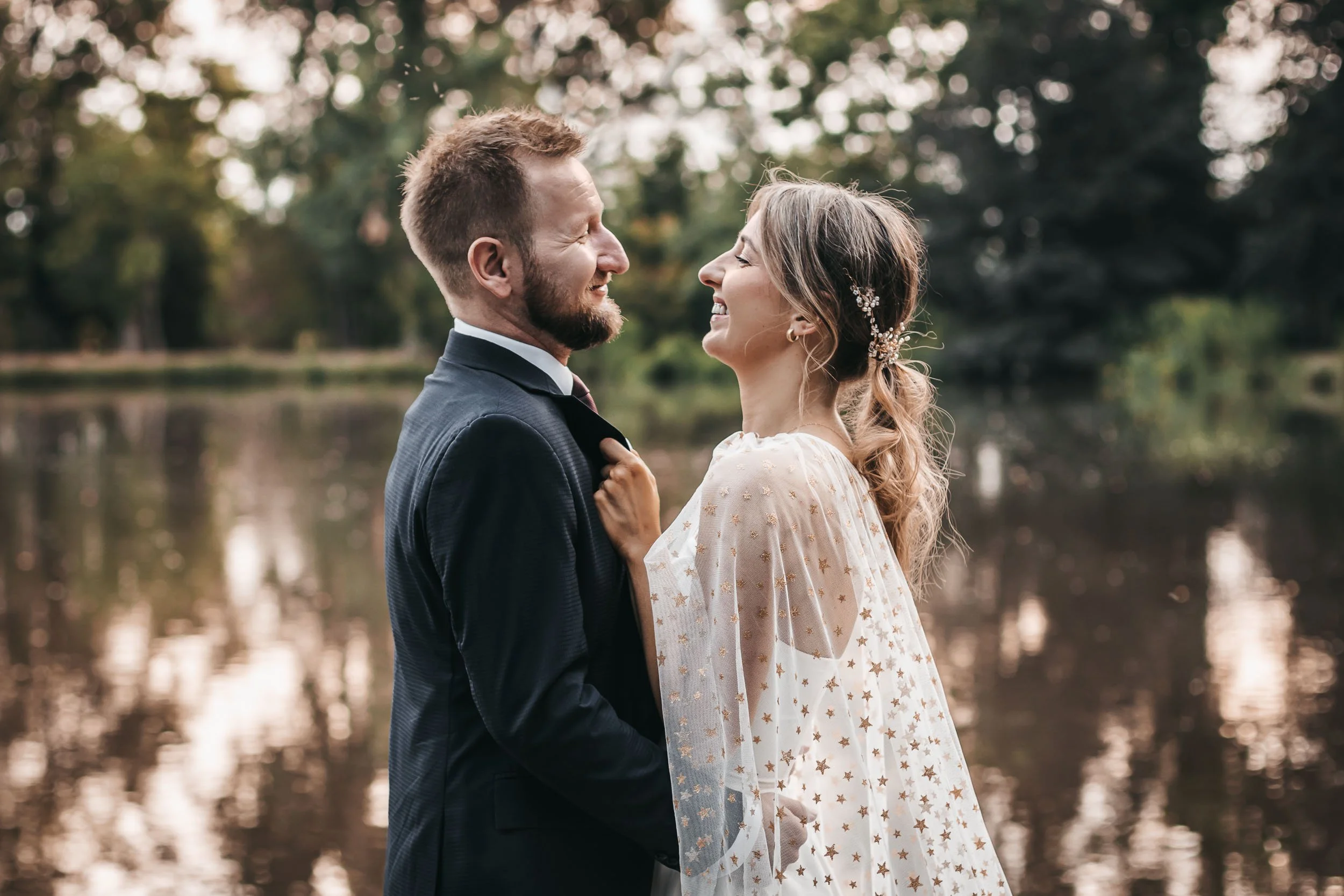 Close portrait of the bride and groom standing together by the lake
