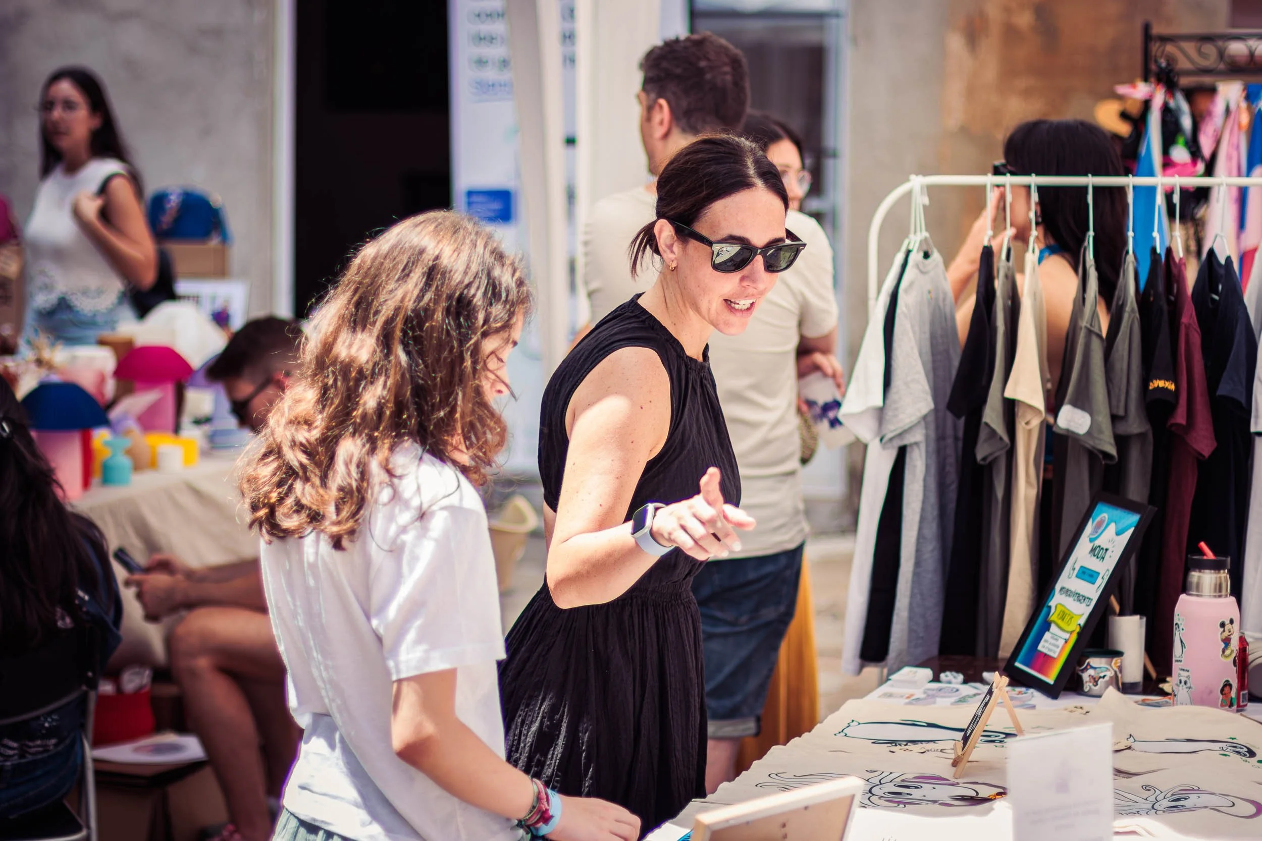 Two visitors browsing products and printed materials at a stall