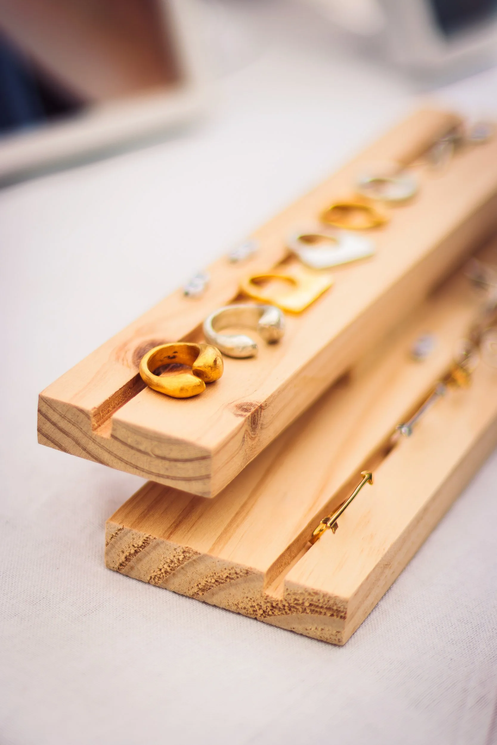 Gold jewellery arranged on stacked wooden display trays at a showroom event