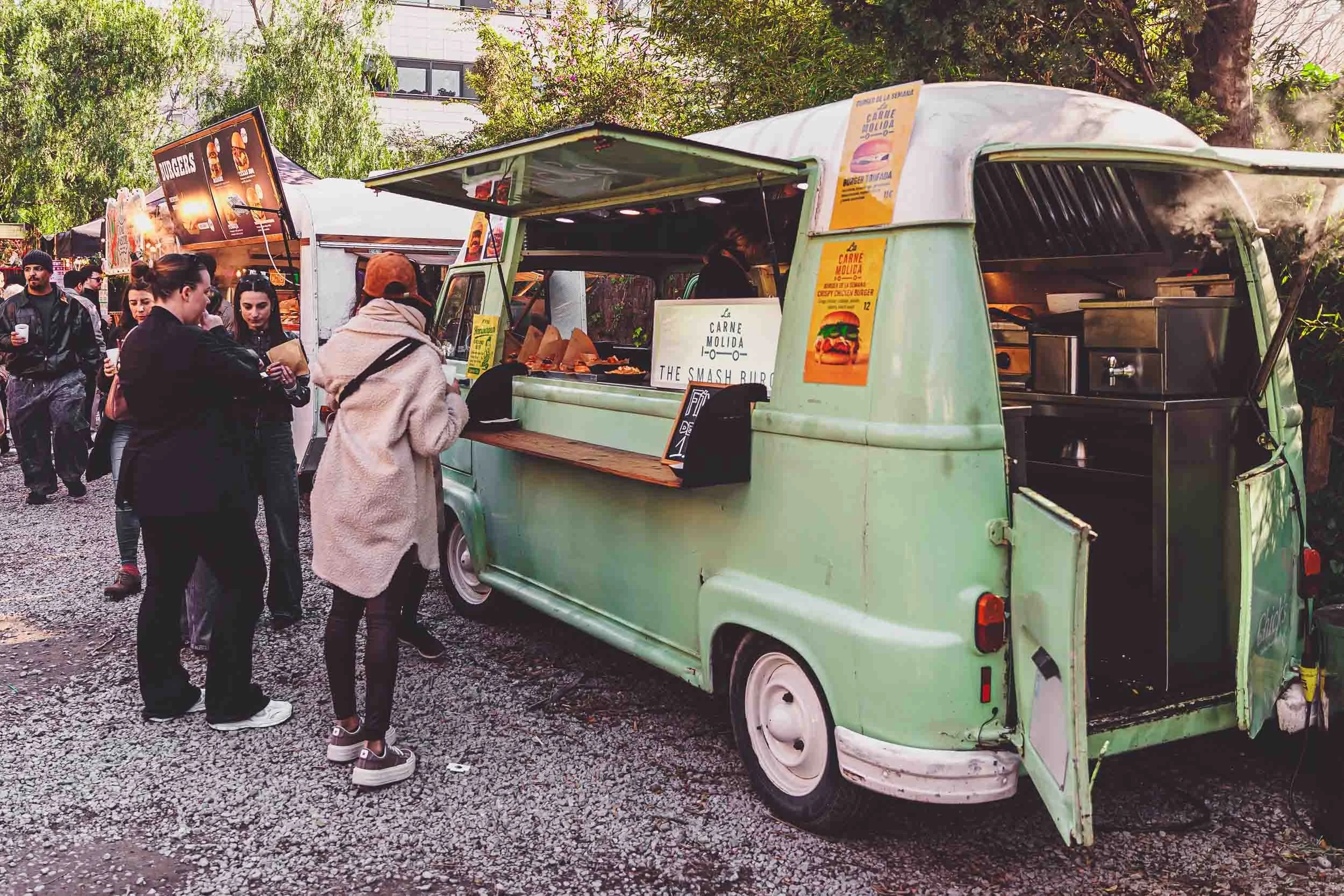 Guests standing beside a green food truck during an outdoor event