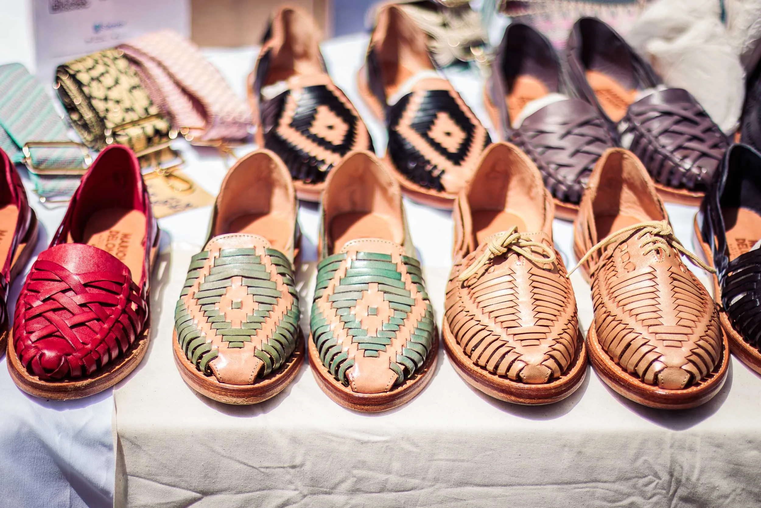 Assorted handmade shoes arranged side by side on a display table at a Barcelona event