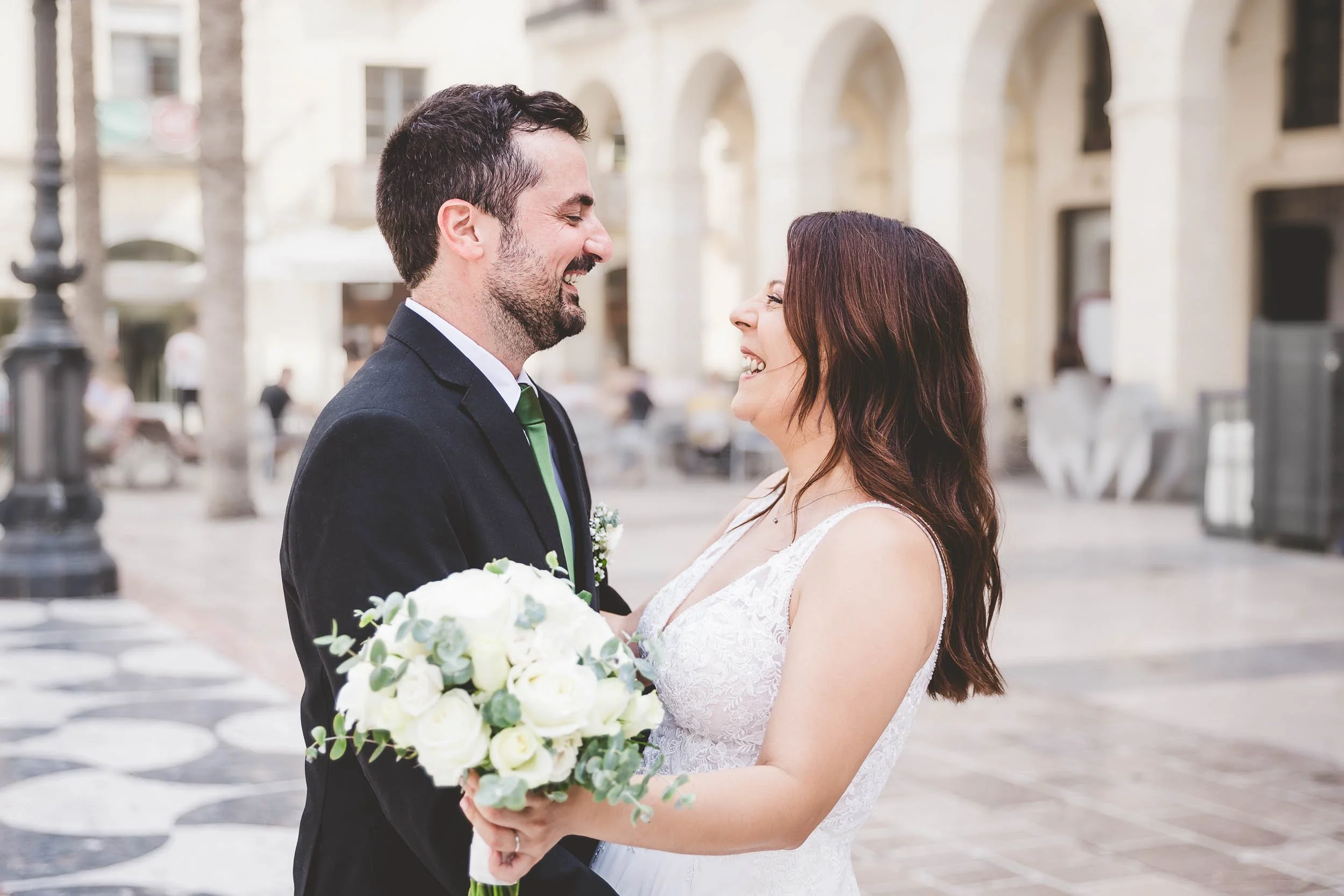 Bride and groom smiling at each other during a wedding portrait in the city square