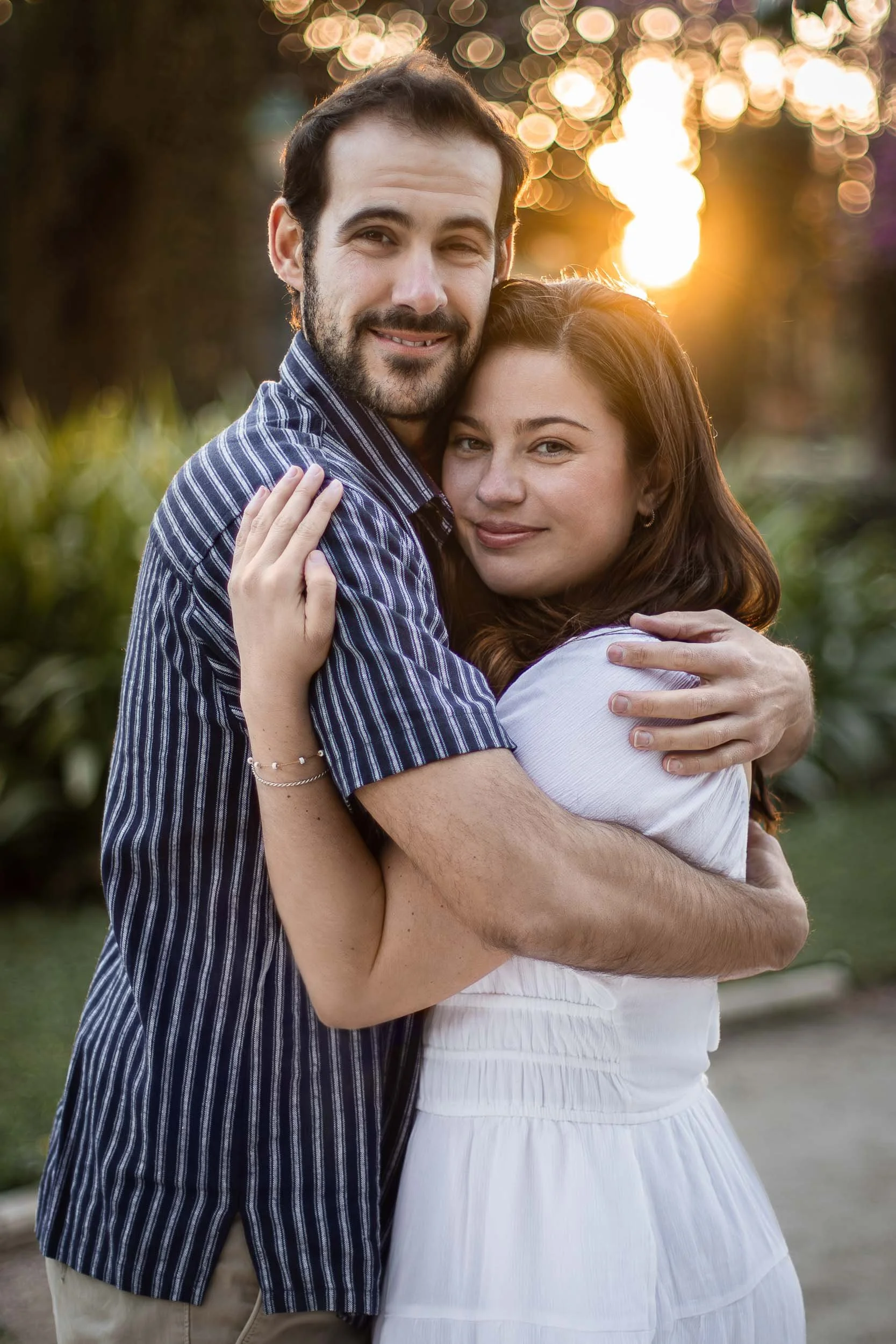 Portrait of a couple embracing and looking toward the camera at sunset