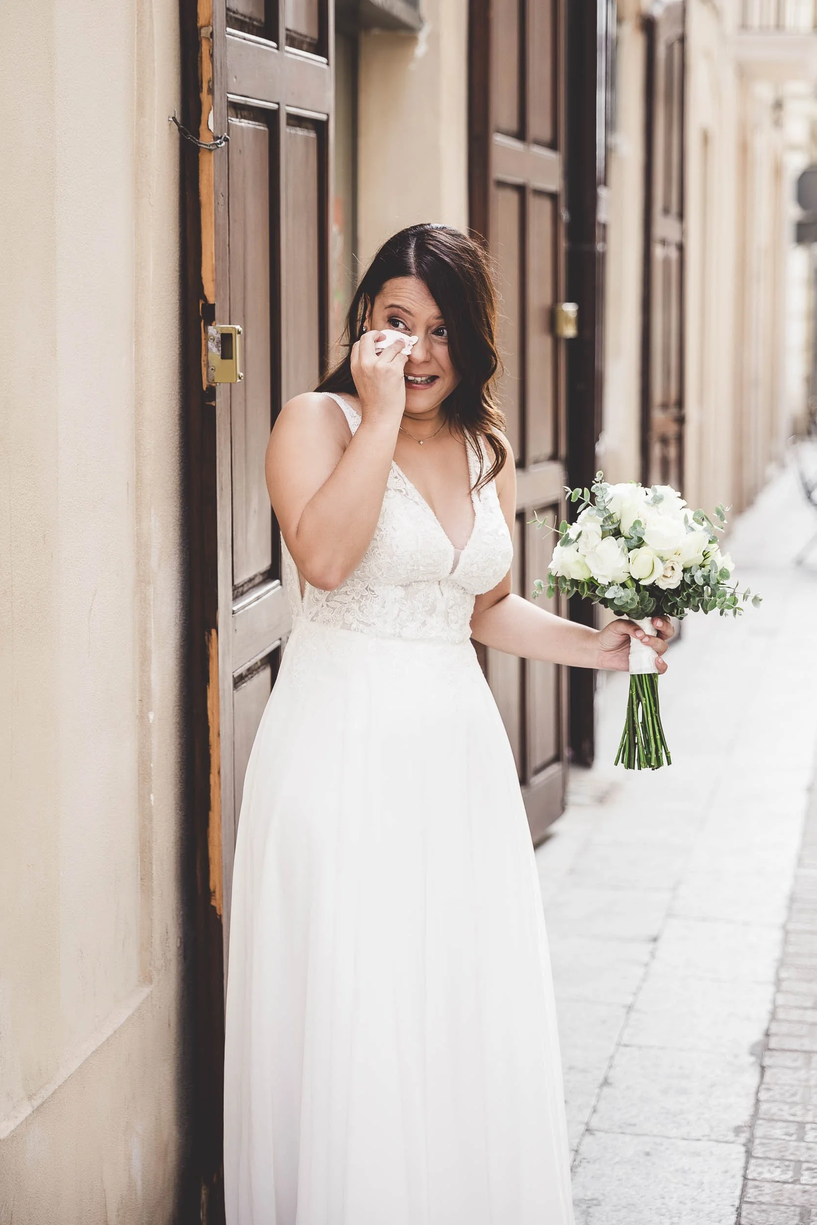 Bride holding her bouquet and wiping away happy tears before the wedding ceremony