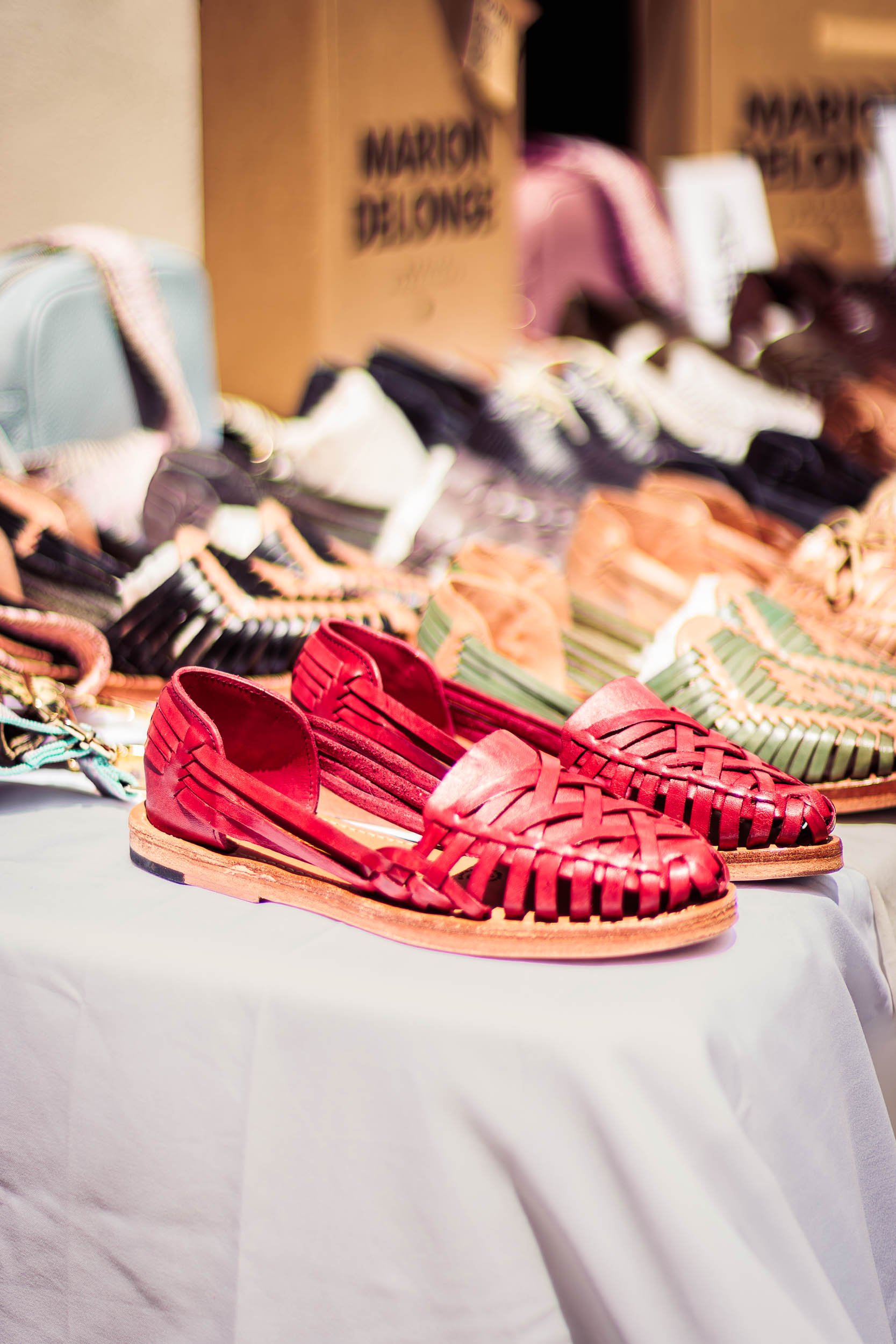 Close-up of red woven leather shoes displayed on a table at a lifestyle event