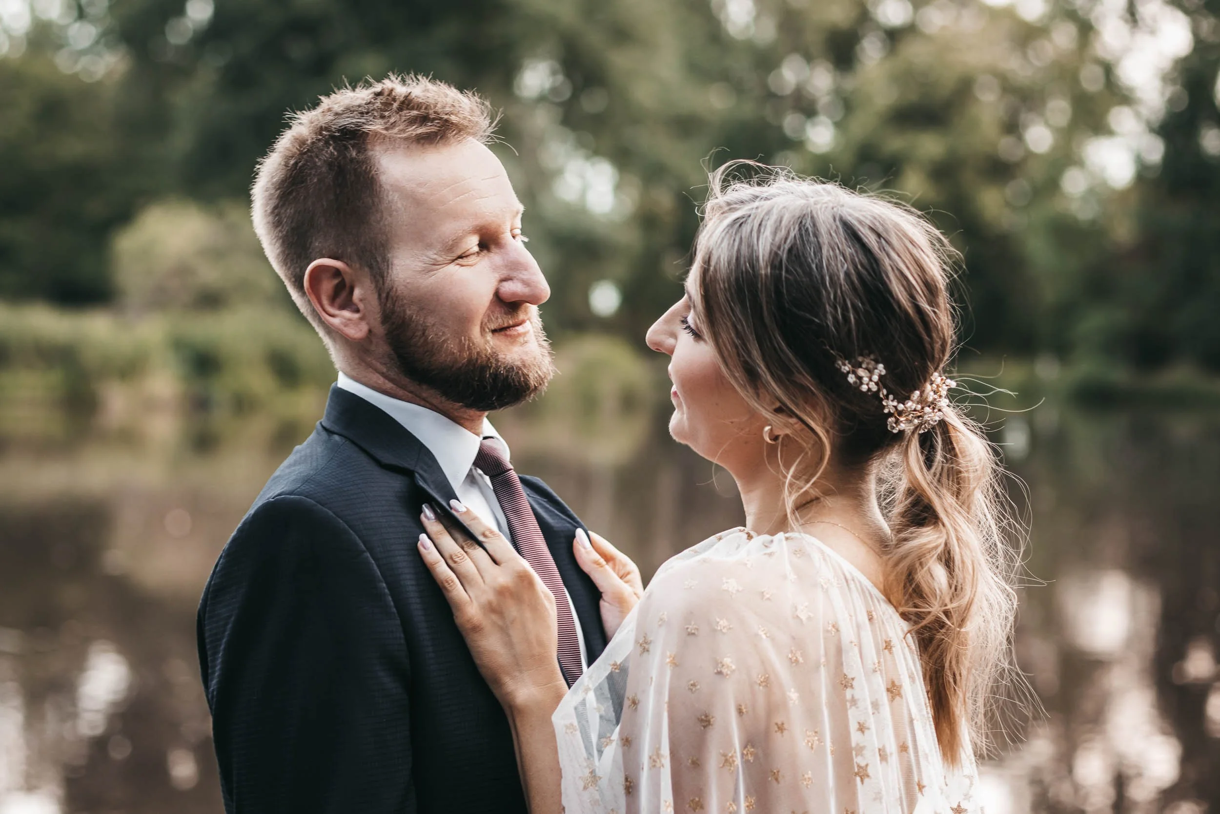 Close wedding portrait of the bride and groom looking at each other by the lake