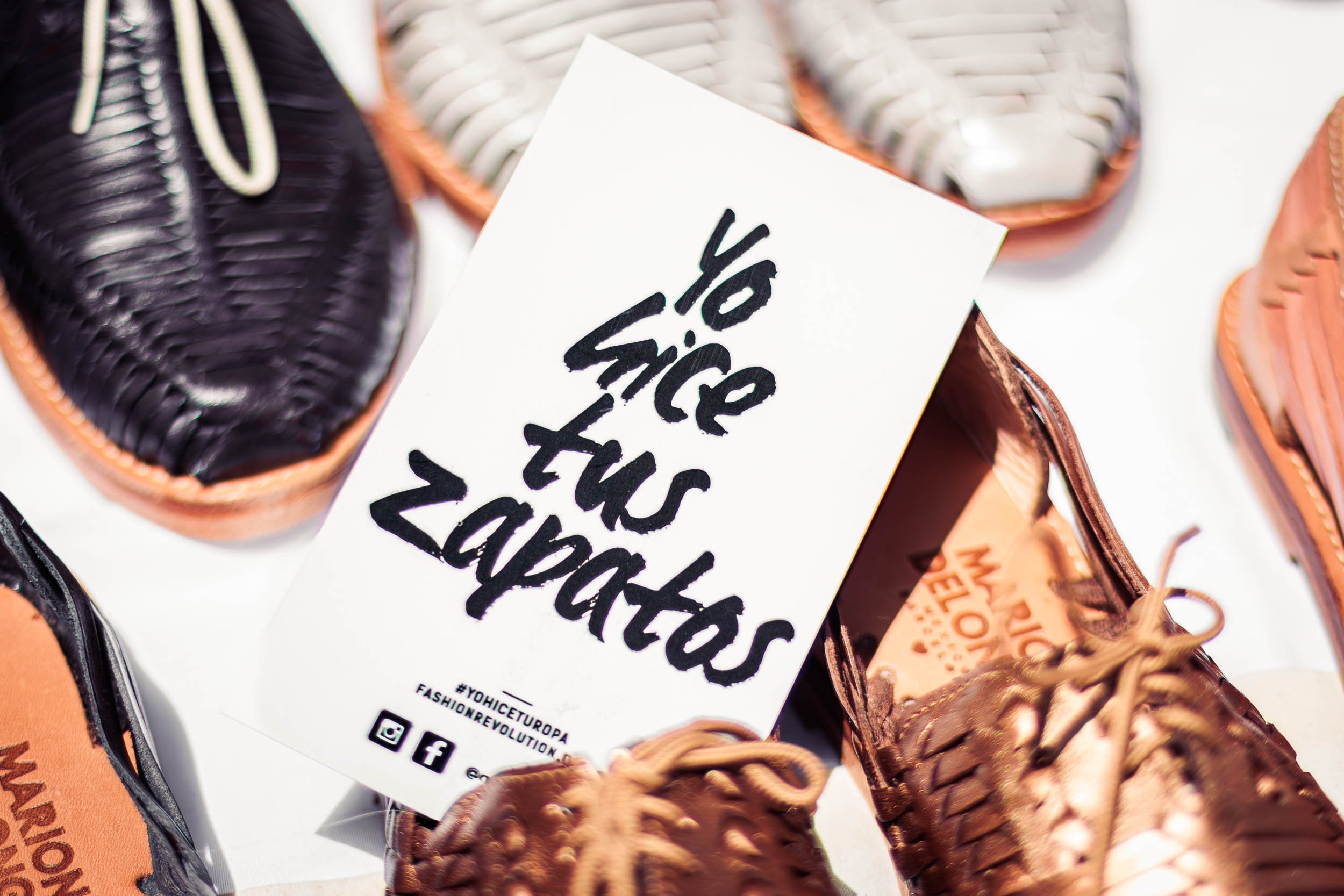 Handcrafted shoes displayed beside a branded sign at a showroom event