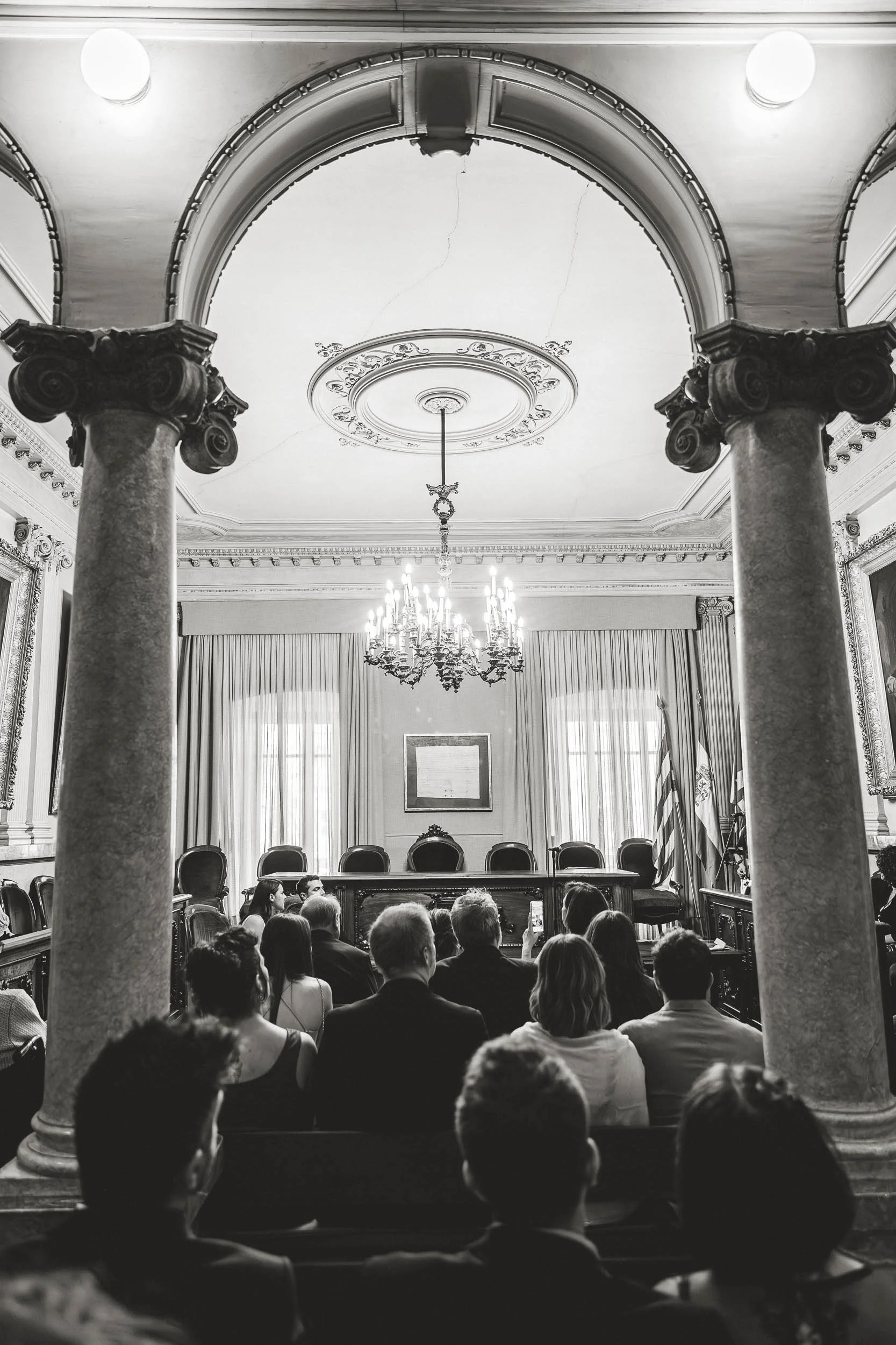 Guests seated inside an elegant city hall ceremony room in black and white