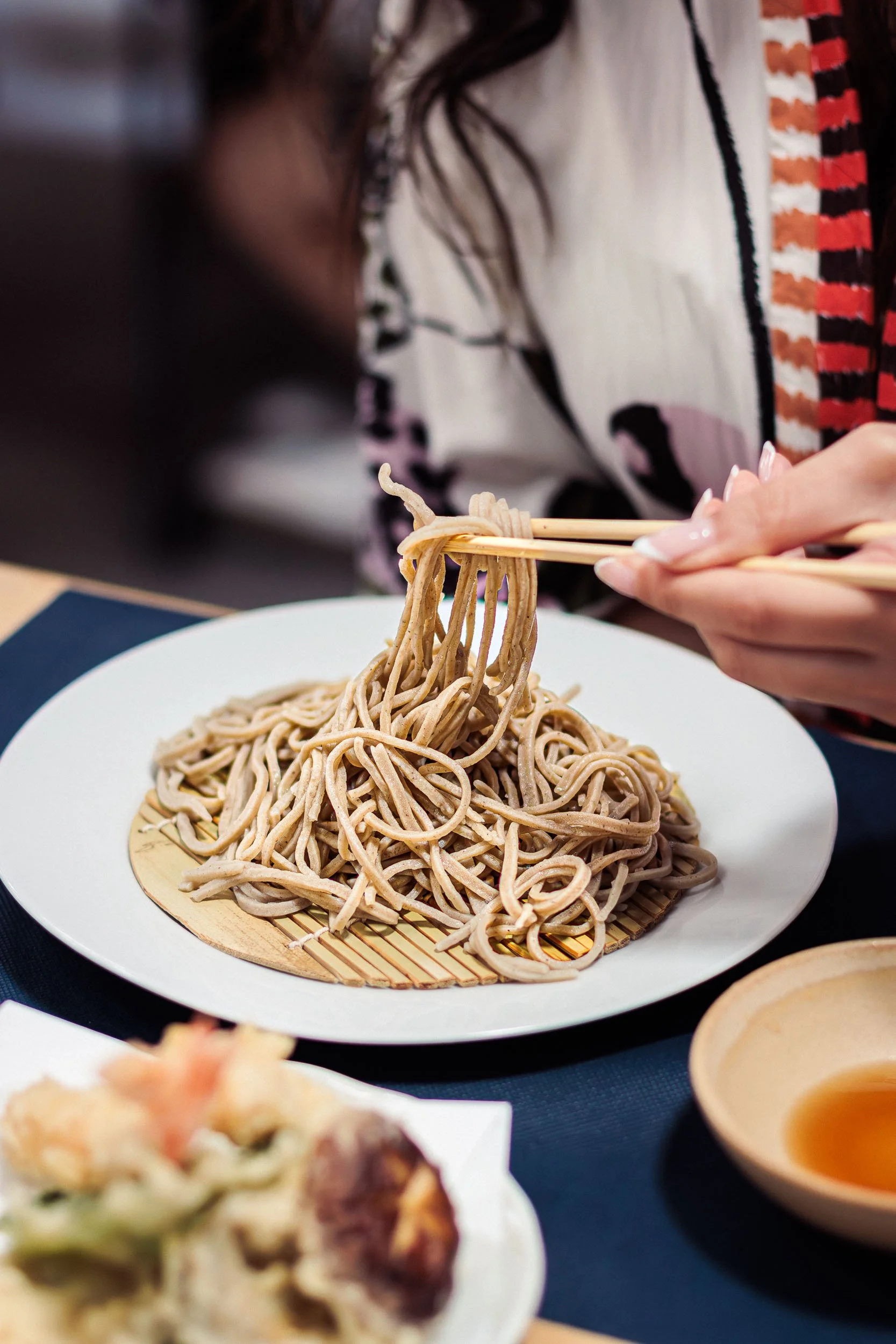 Close-up of soba noodles being lifted with chopsticks at the table in a Barcelona restaurant