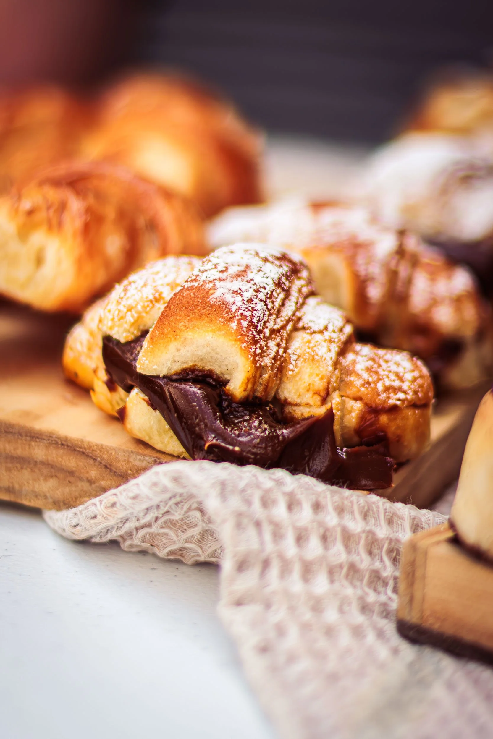 Close-up of croissants and pastries arranged on a wooden serving board at a showroom event 
