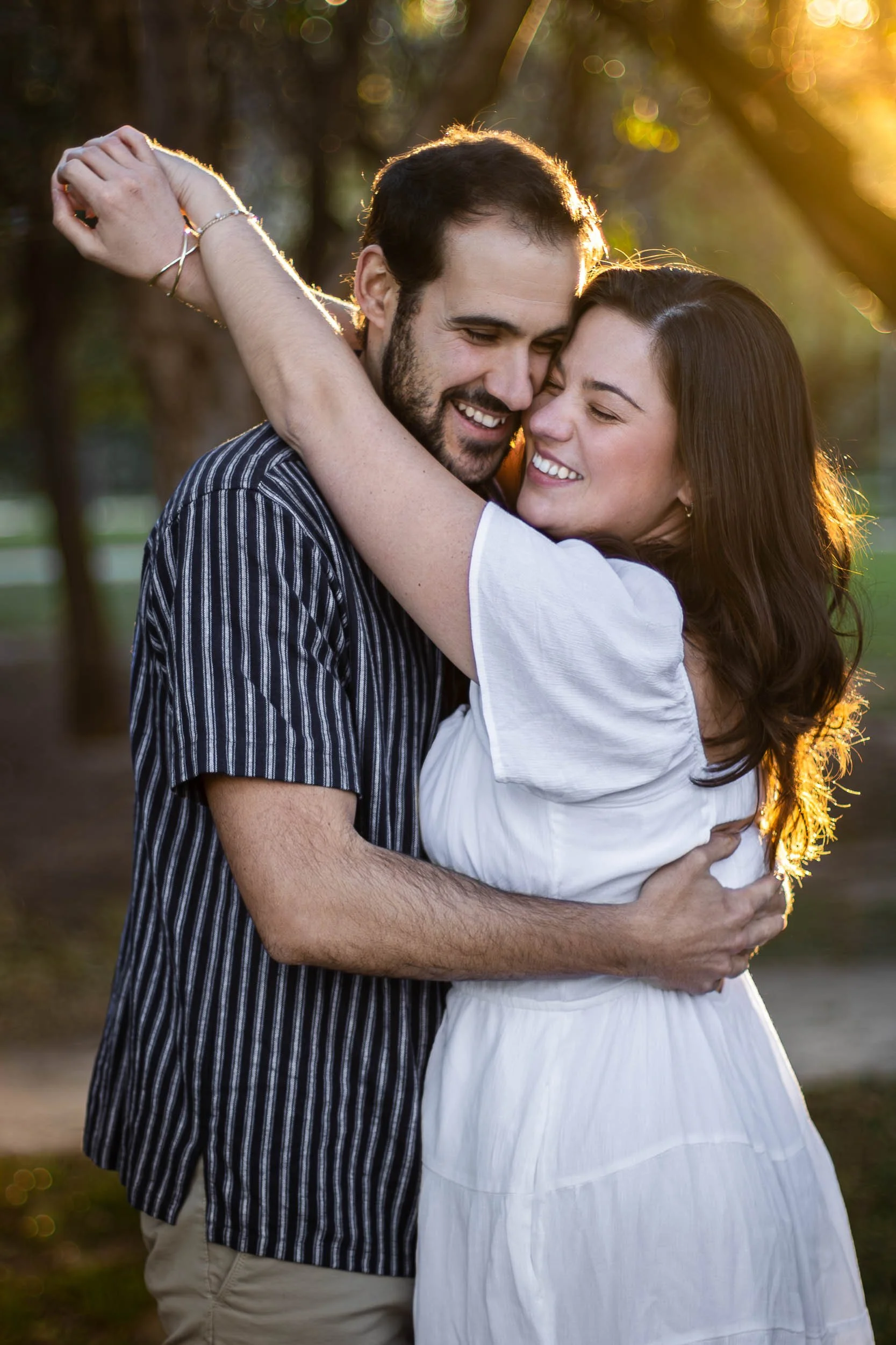 Portrait of a couple embracing in warm golden-hour light in a park