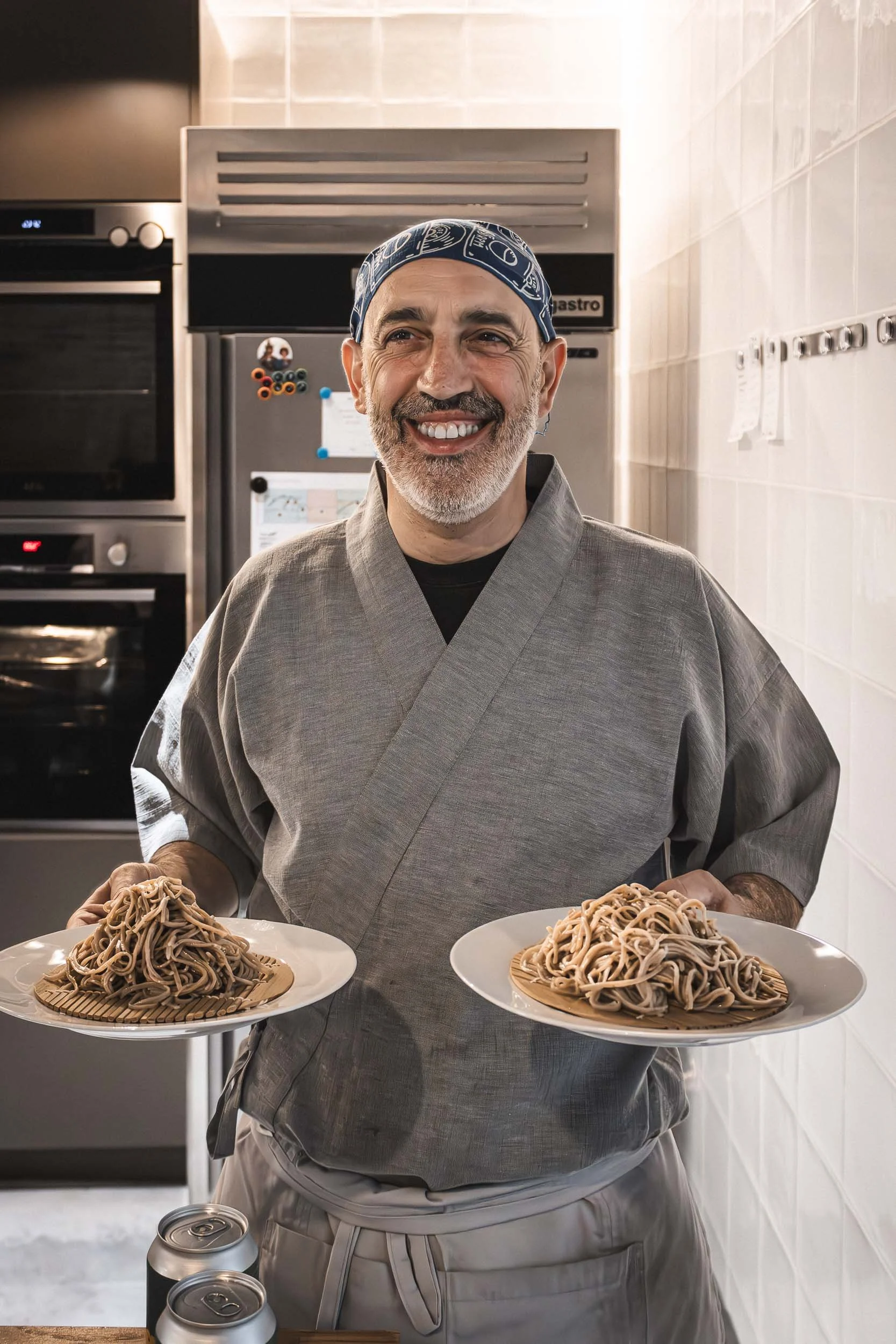 Chef holding two plates of soba noodles in the kitchen