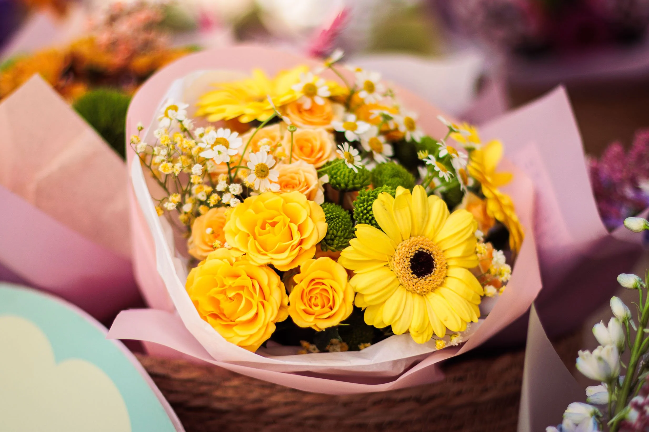 Product photography of a yellow flower bouquet wrapped in decorative pink paper 