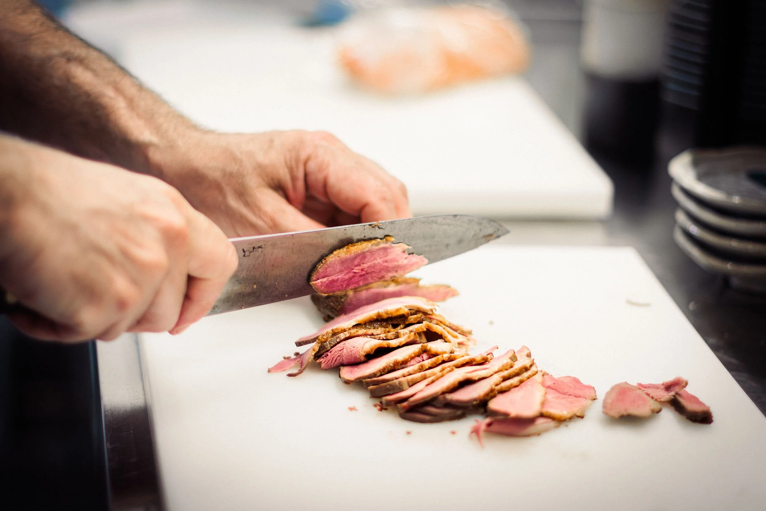 Close-up of sliced meat being prepared on a cutting board in the kitchen